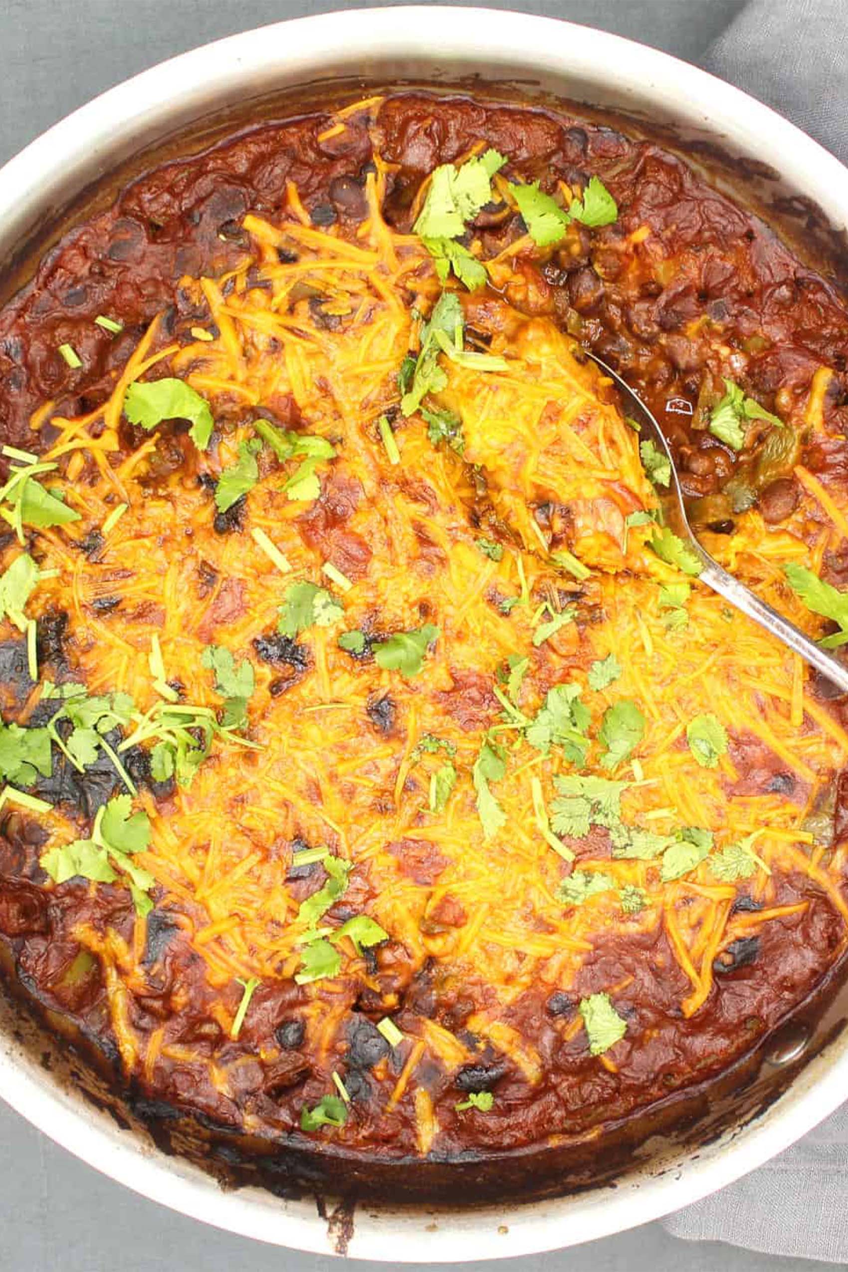 a baked dish of black beans topped with vegan cheese