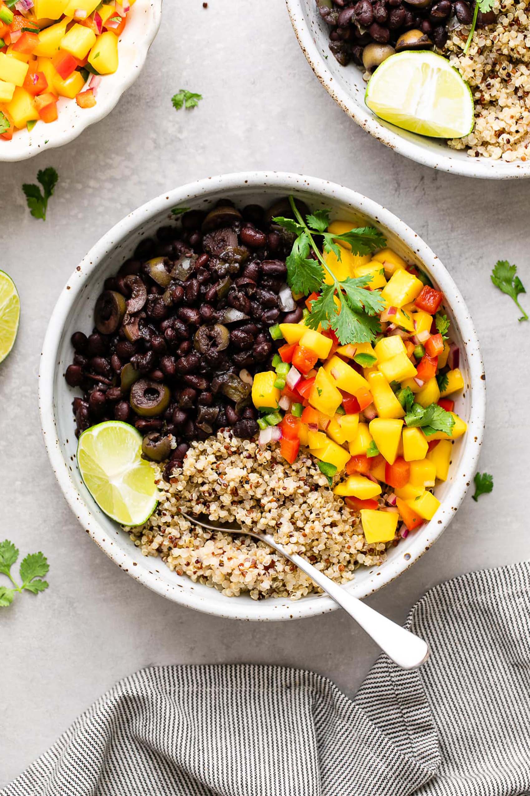 a bowl of rice, tricolor peppers and beans served with a wedge of lime