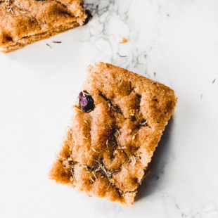 overhead image of brown square piece of bread with olives and rosemary