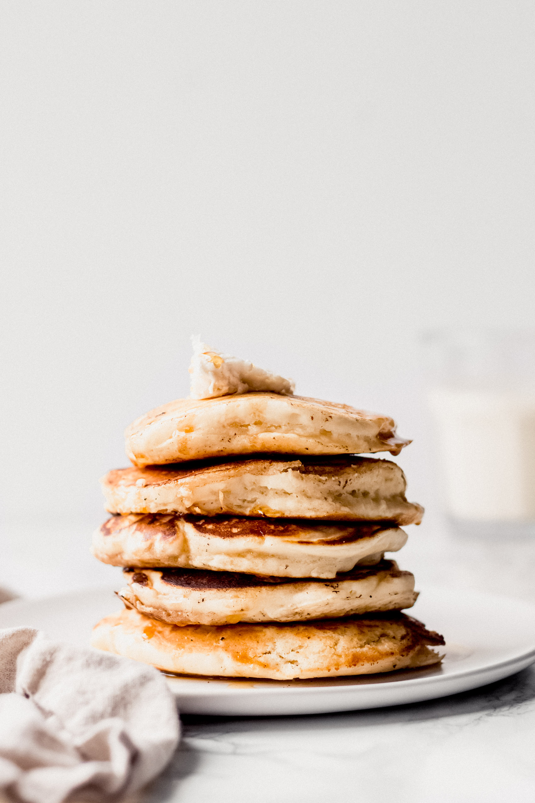 a stack of five pancakes topped with a pat of vegan butter