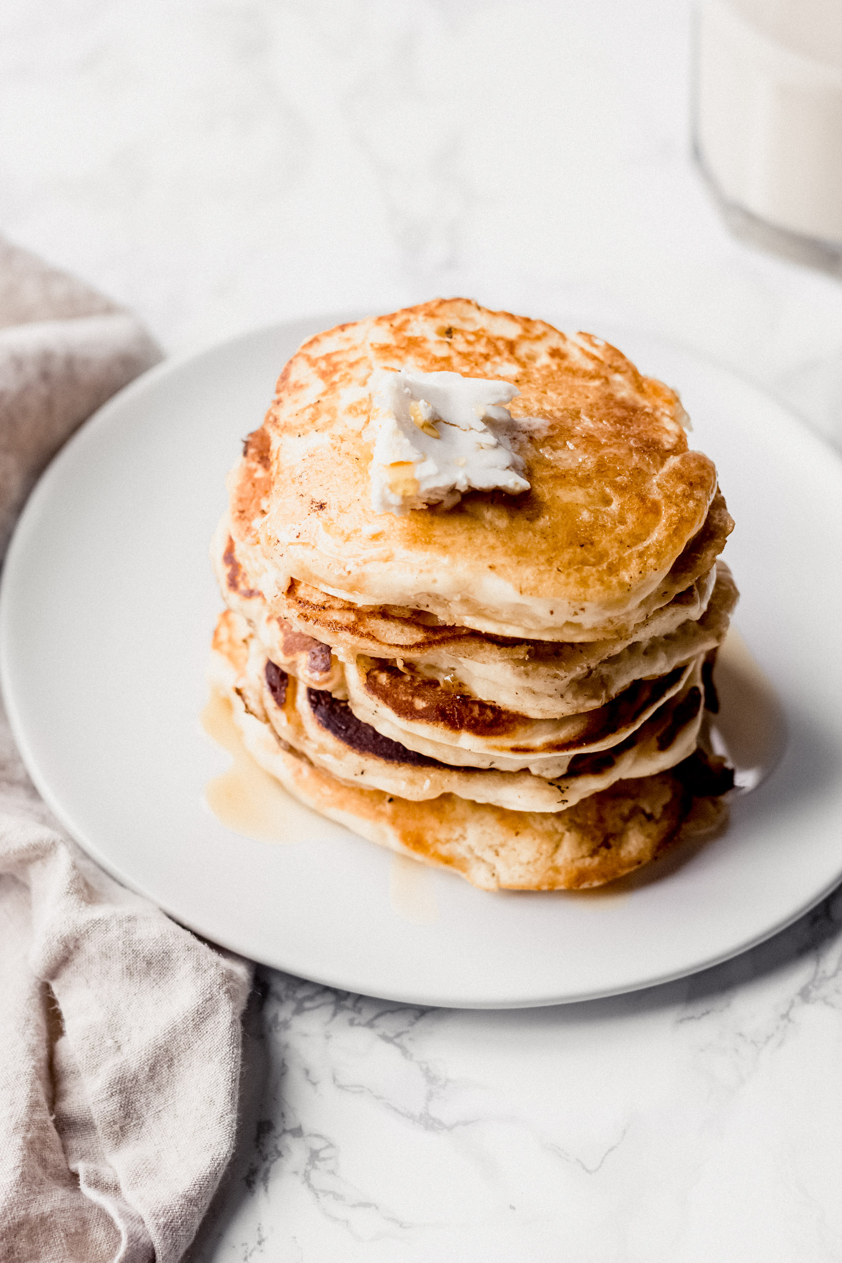 an overhead shot of a plate of pancakes served with maple syrup and butter