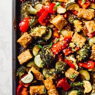 a sheet tray of roasted vegetables and tempeh topped with white sesame seeds