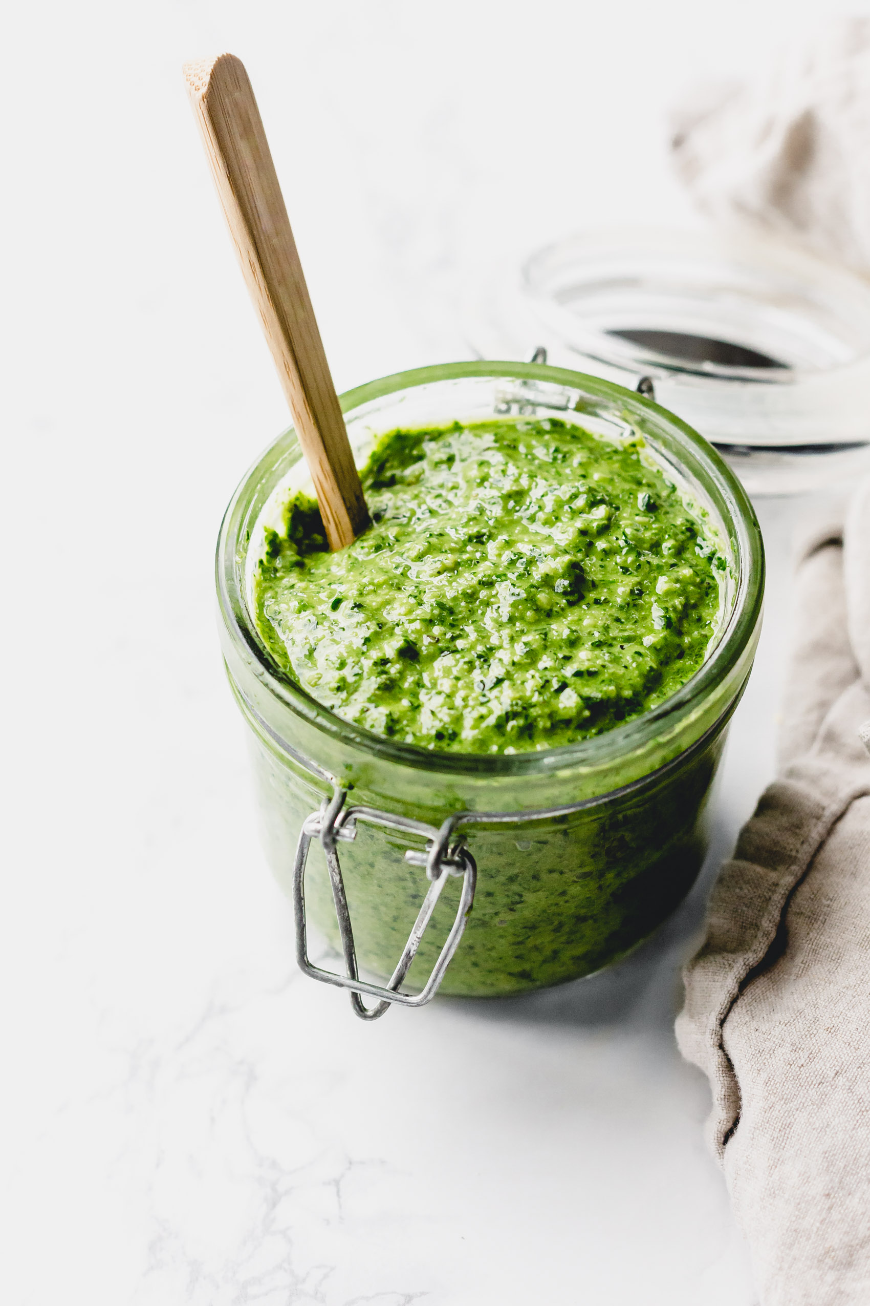 a spoon stirring a jar of pesto