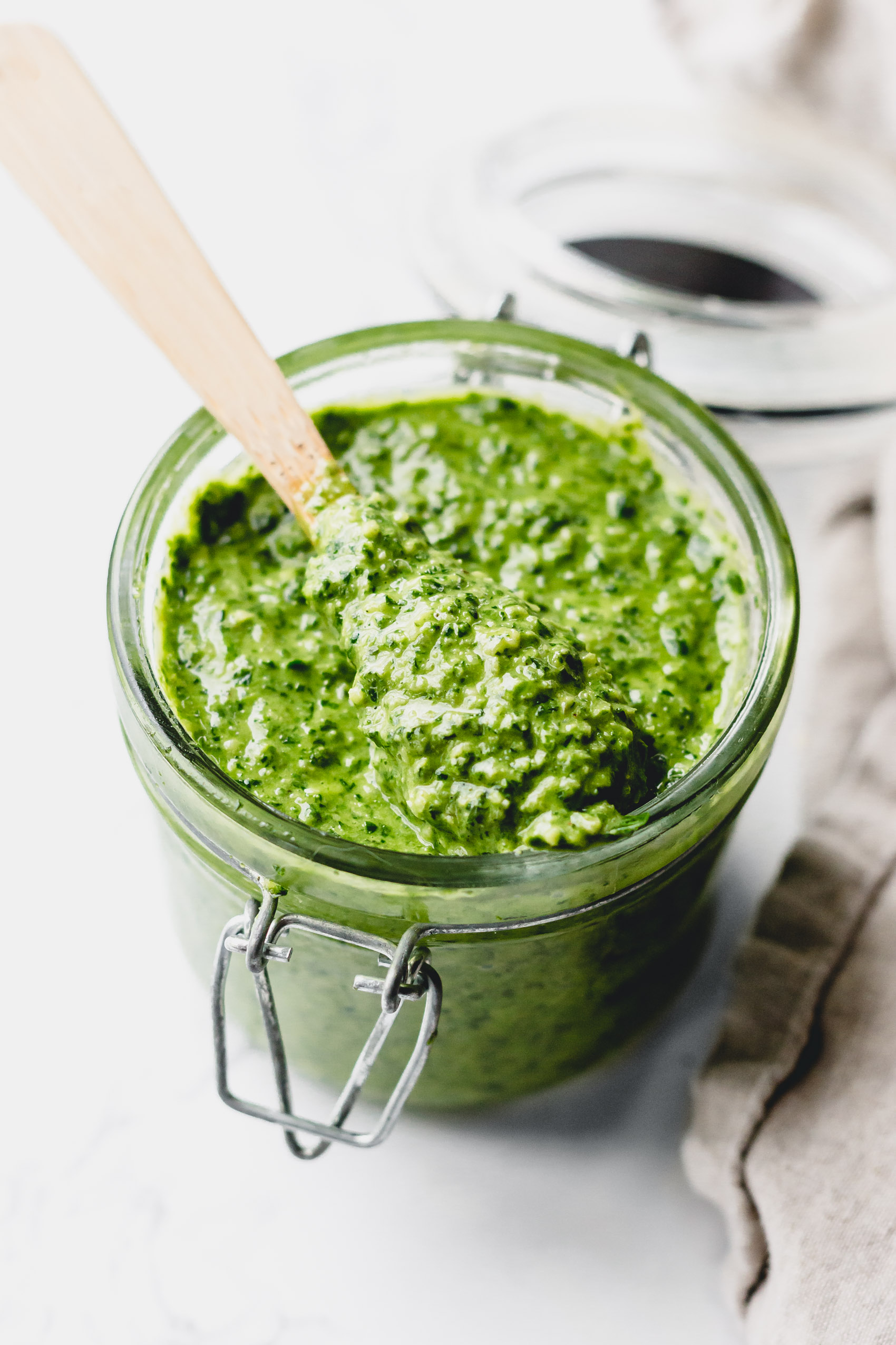 a spoon taking a scoop of pesto out of a jar