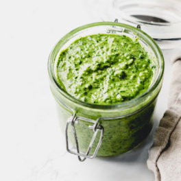 a jar of pesto resting next to a dish towel