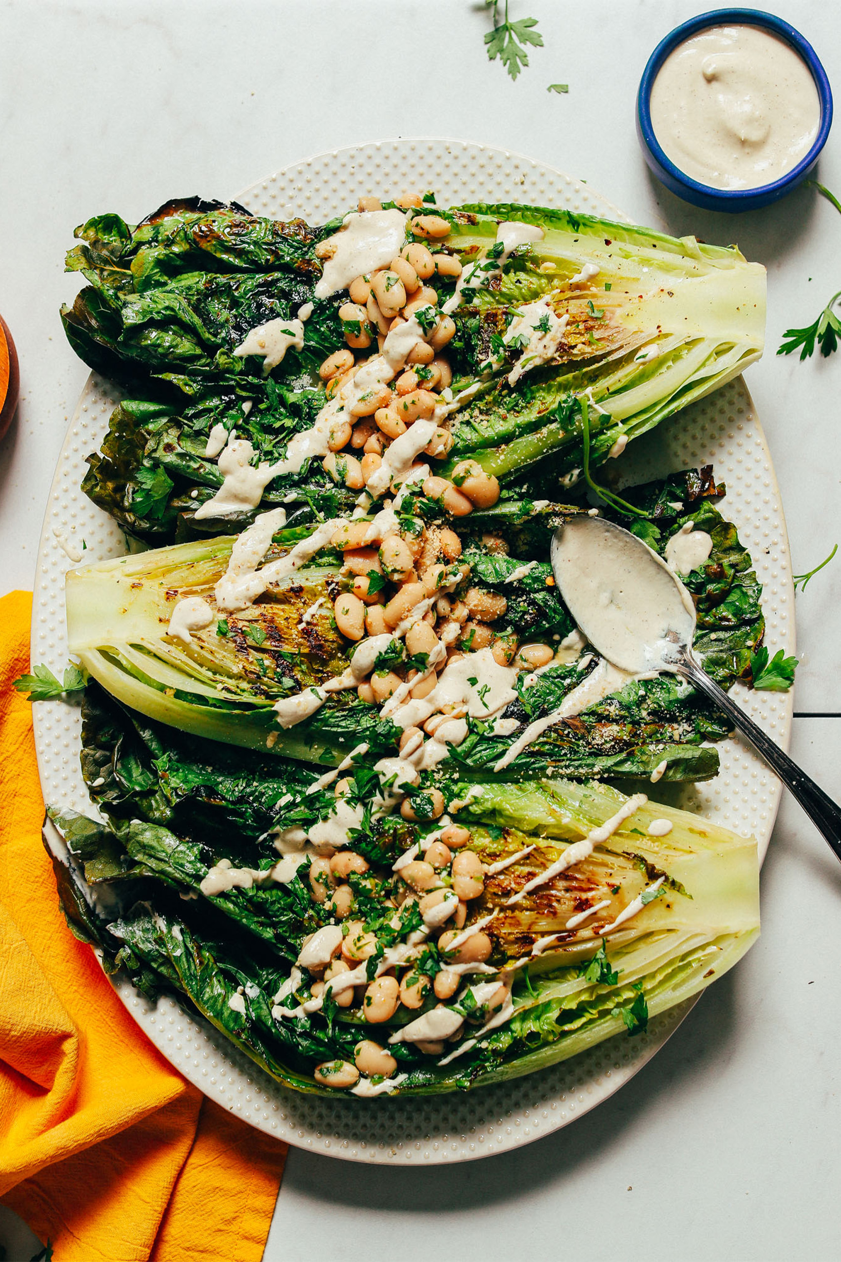 a plate of a vegan grilled caesar salad topped with white beans