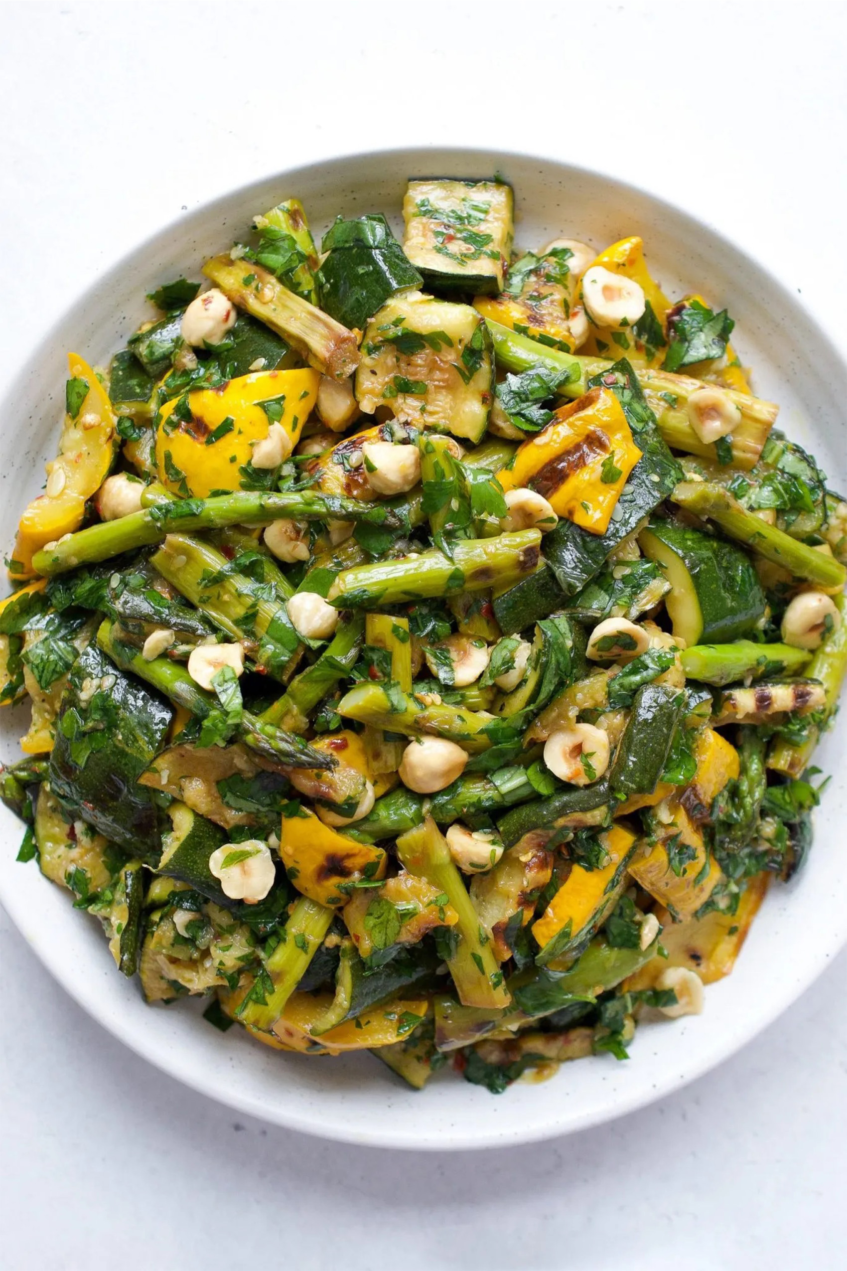 a dish of grilled asparagus and zucchini salad topped with hazelnuts