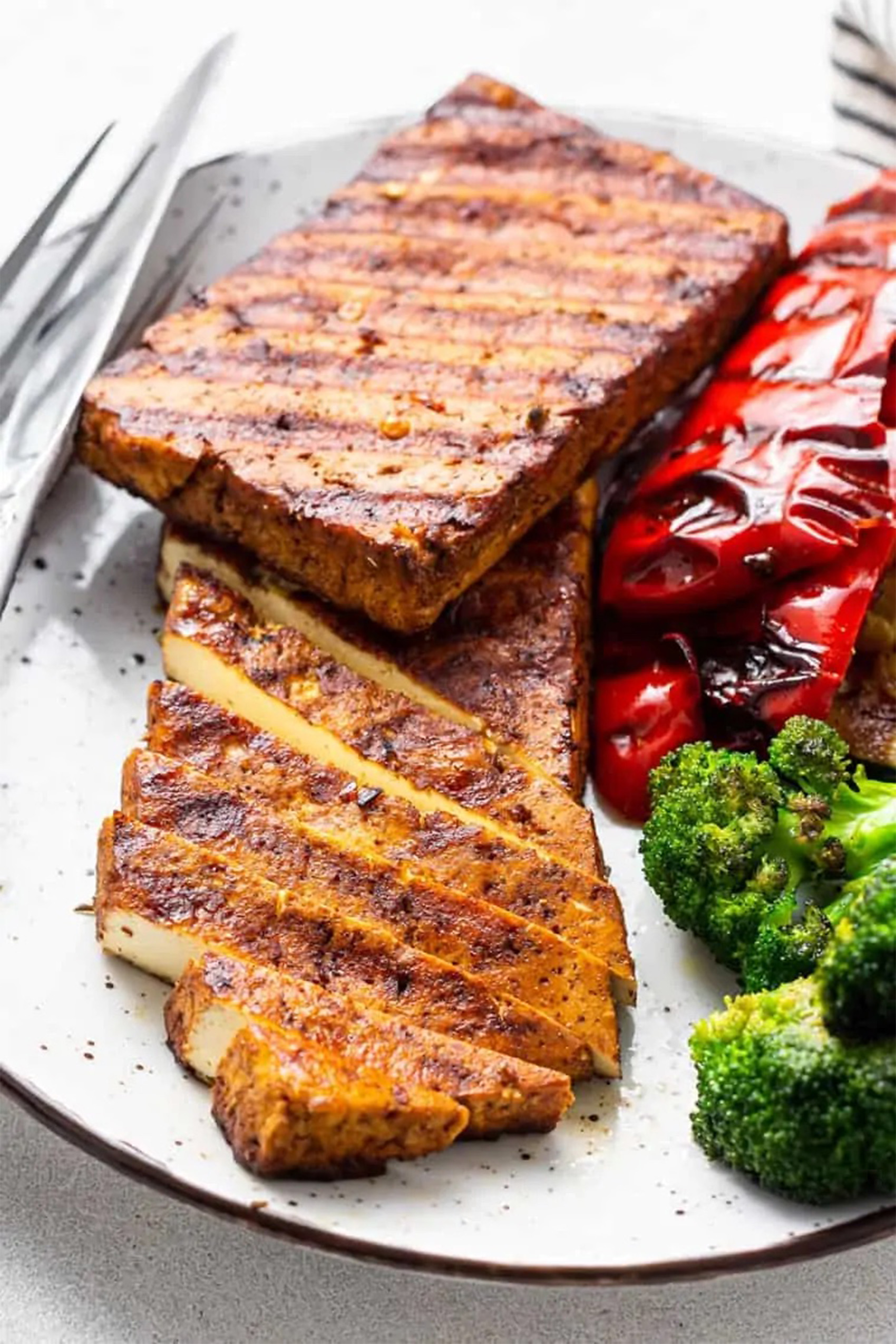 a block of grilled tofu served with vegetables
