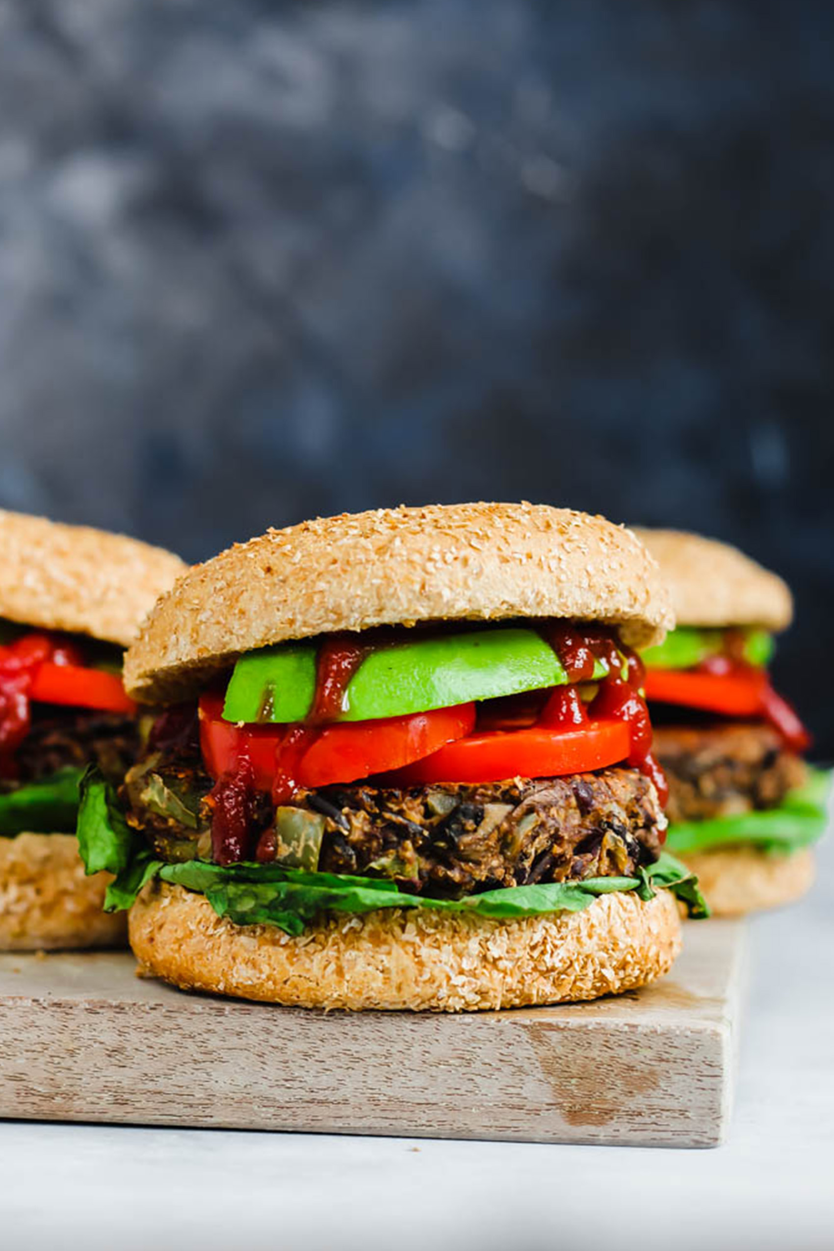 three wild rice veggie burgers topped with tomato, lettuce and ketchup