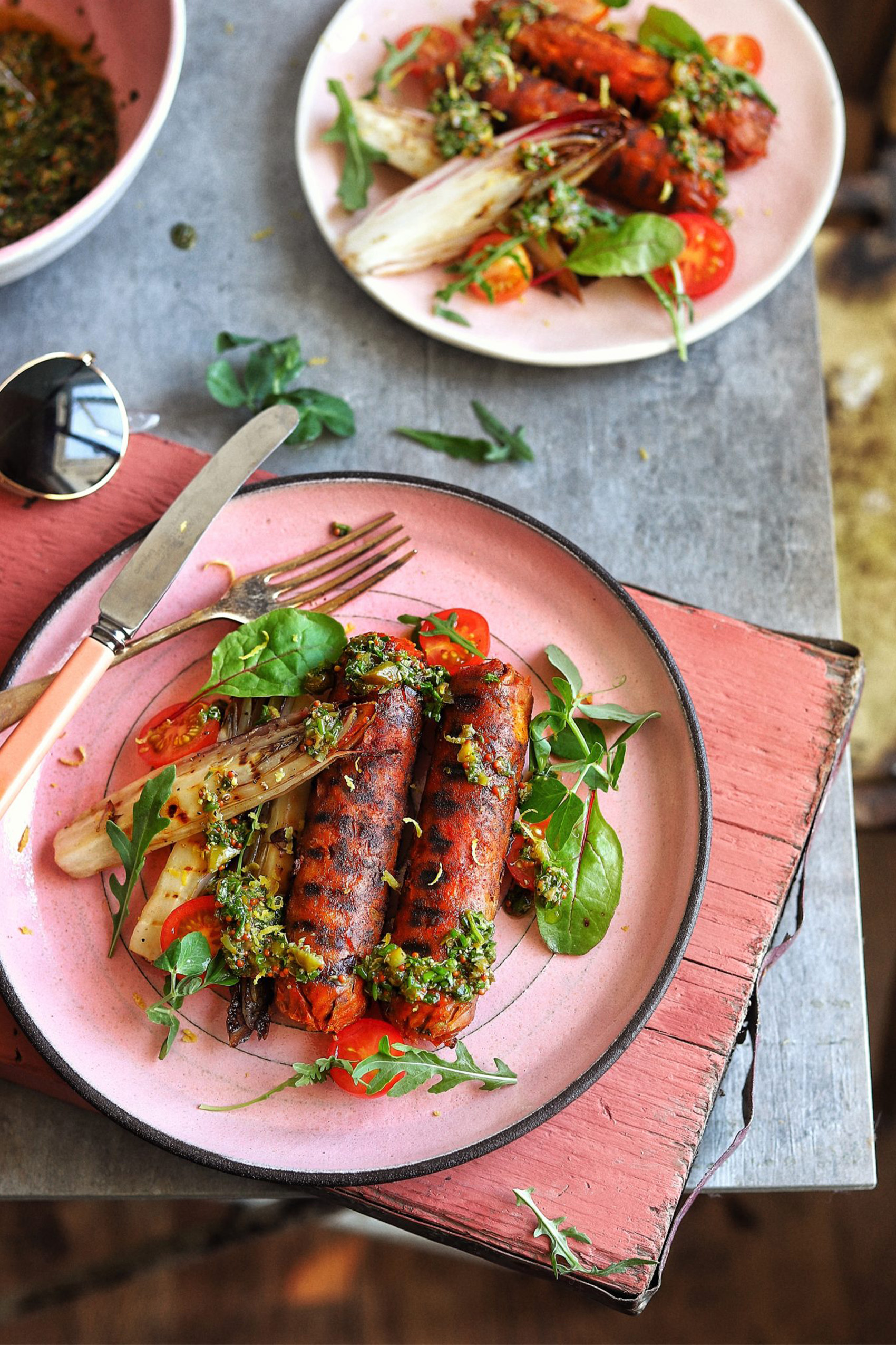 a plate holding two grilled sausages served with greens