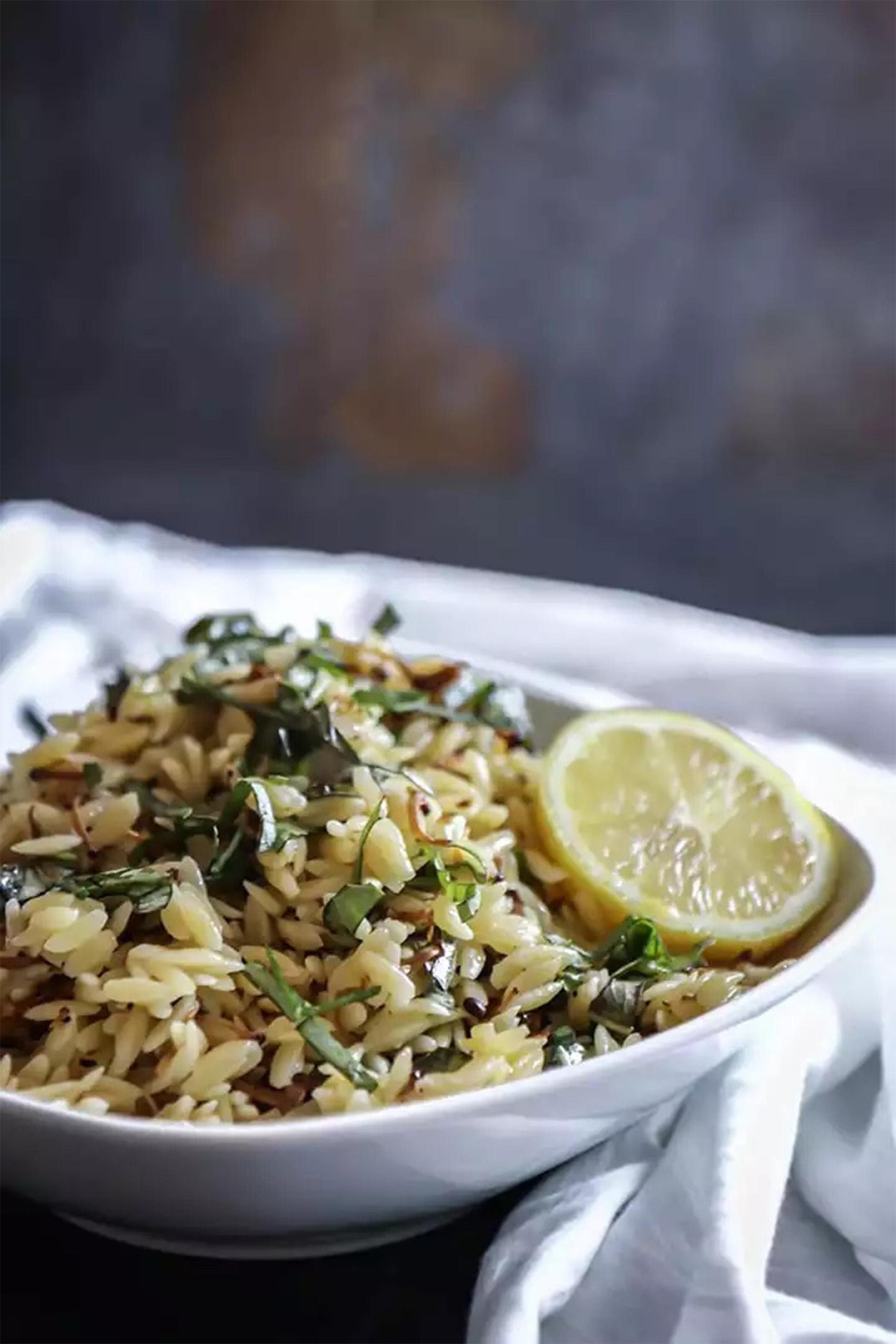 a bowl of mushroom pasta salad served with a fresh lemon