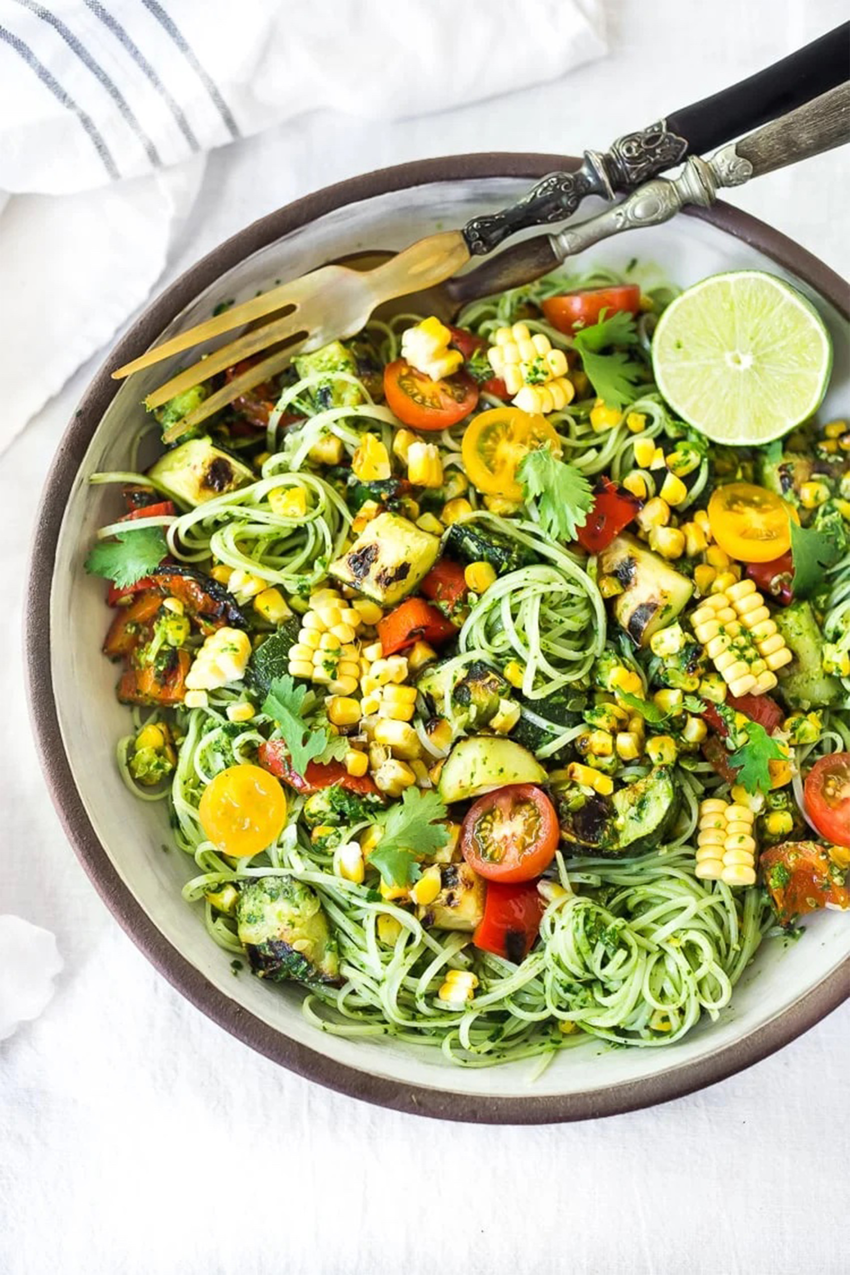 a bowl of summer pasta salad with fresh vegetables and herbs