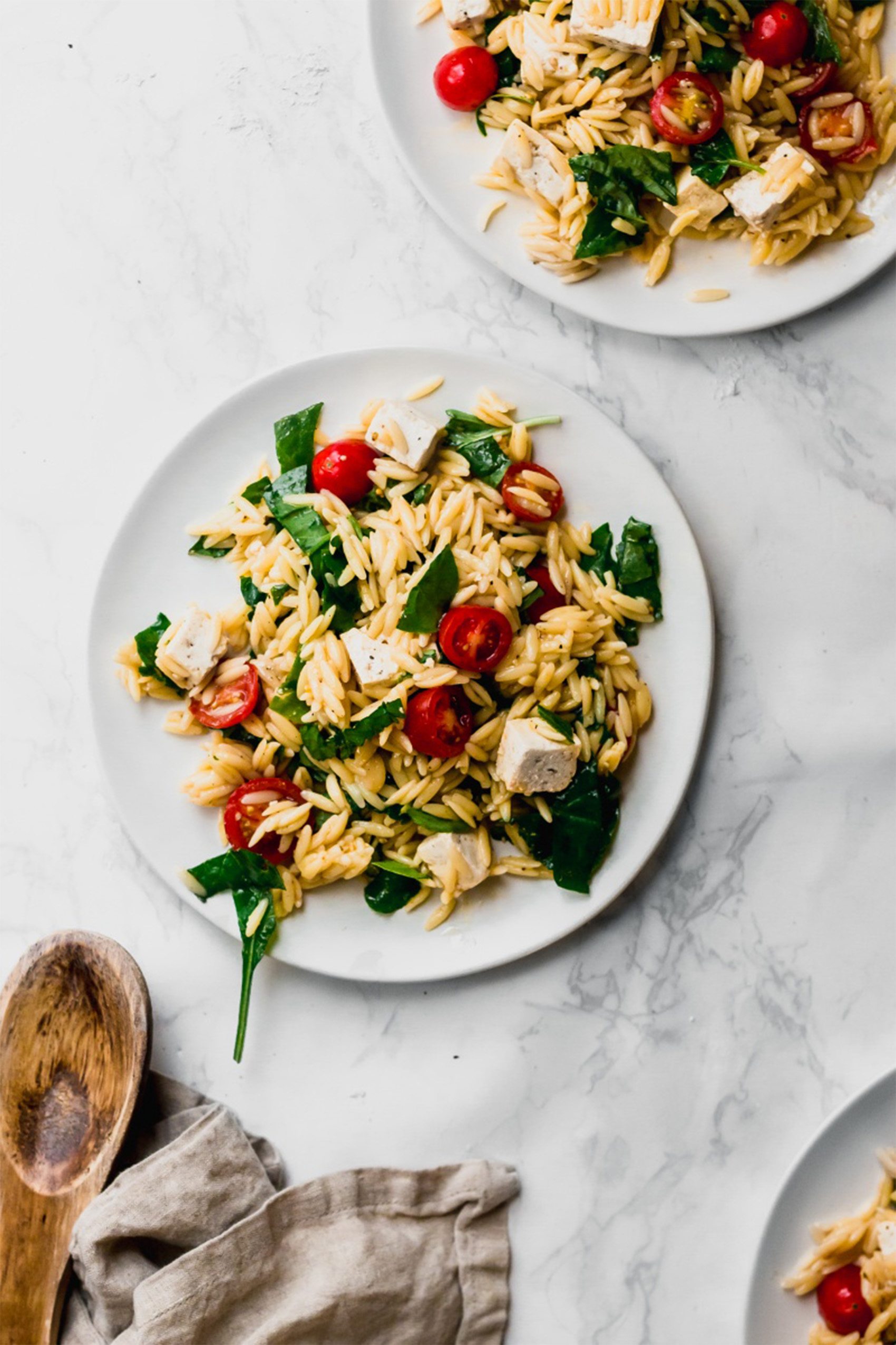 two plates of caprese orzo pasta salad