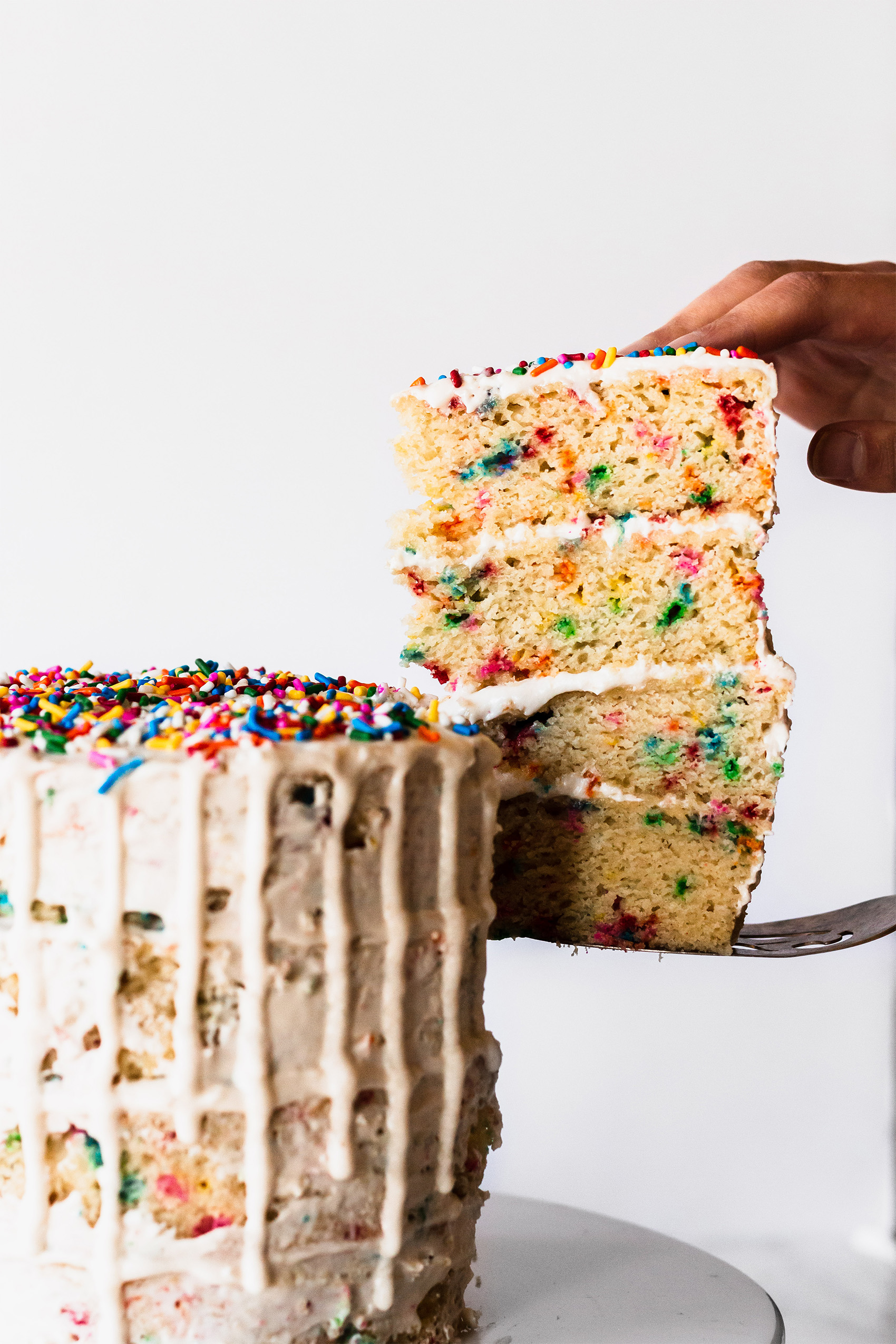 a slice being carved out of a funfetti cake