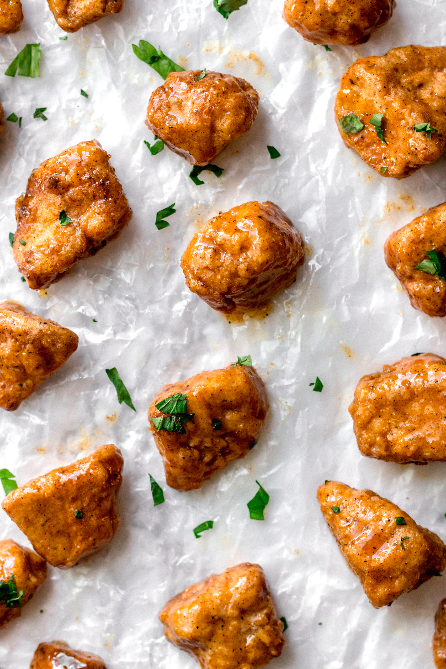 a sheet tray full of vegan chicken nuggets topped with chopped parsley