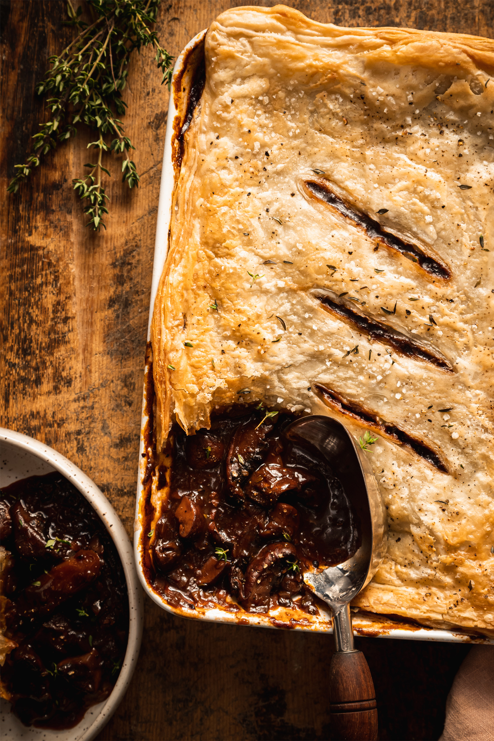 a mushroom pie being sliced into with a wooden spoon