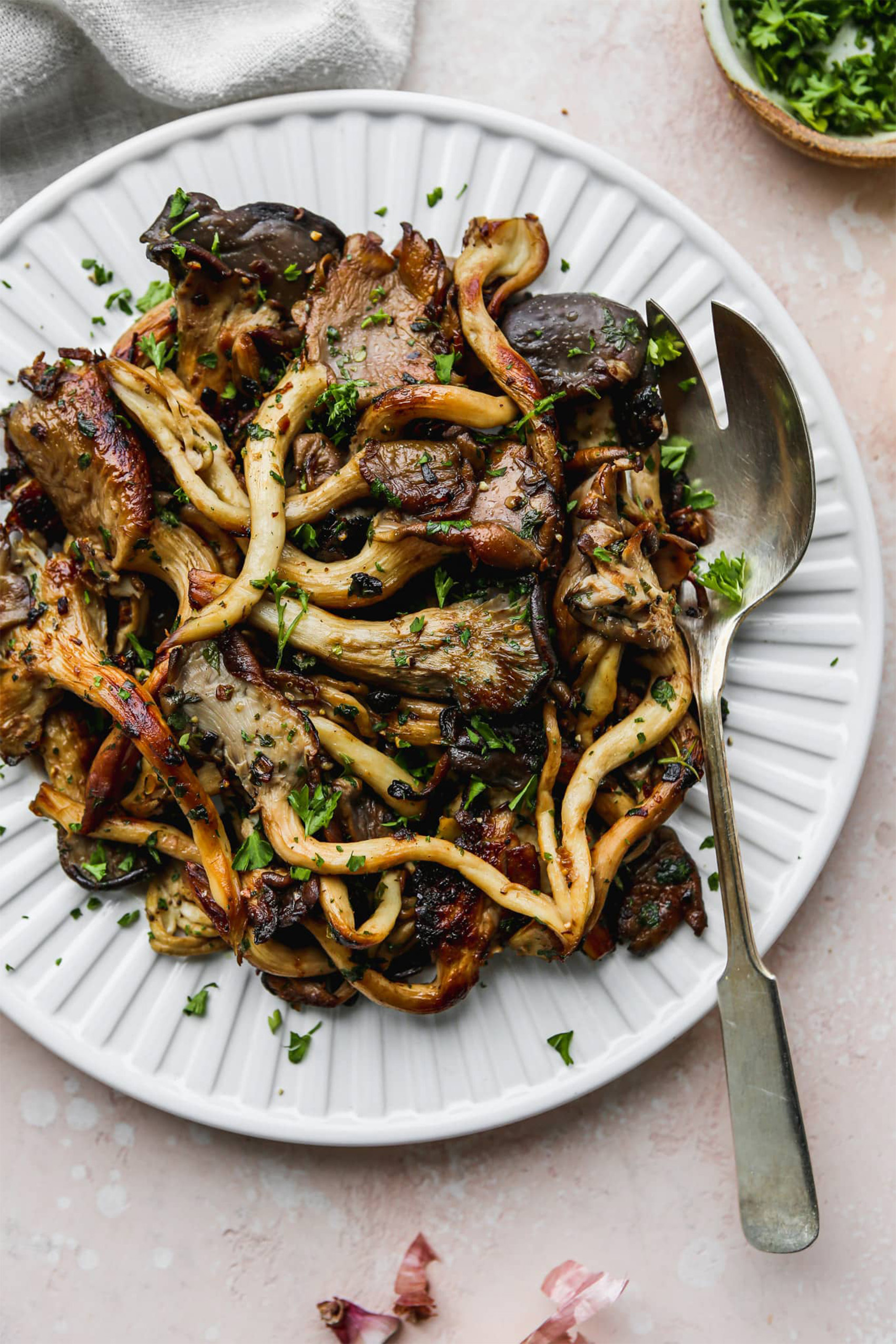 a plate of stir fried mushrooms topped with herbs