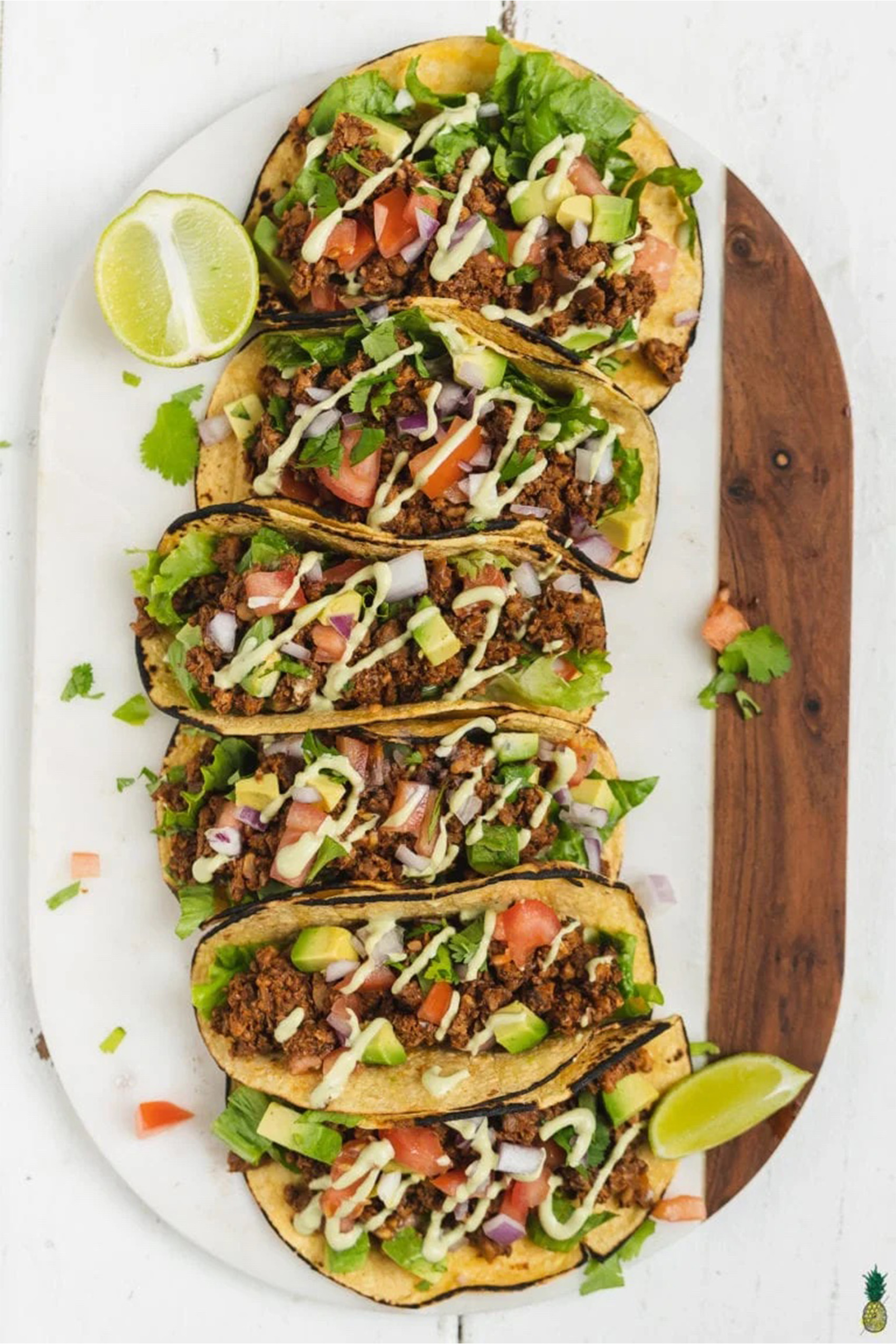 a plate of walnut mushroom tacos served with herbs and lime wedges
