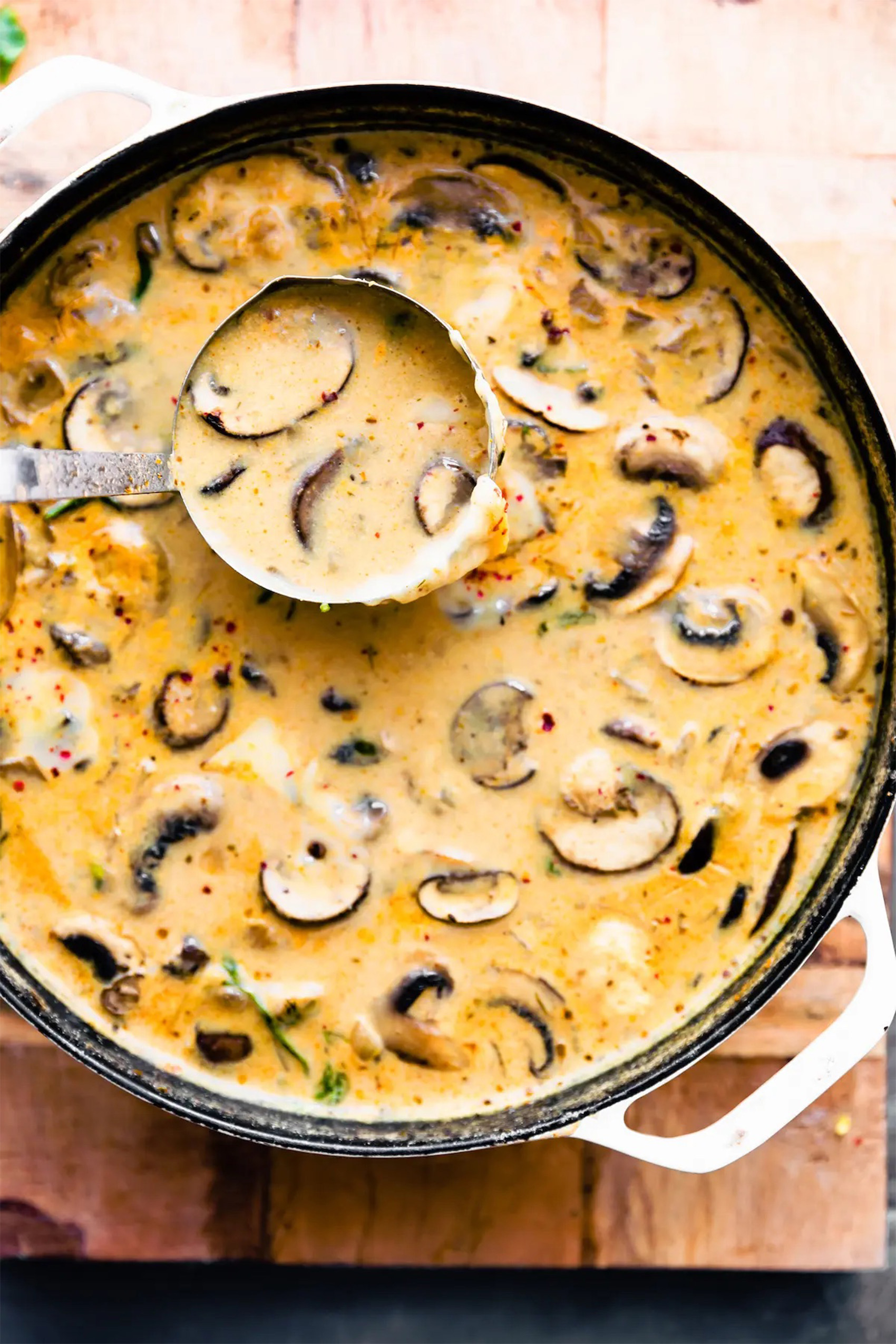 a pot of a creamy mushroom soup being ladled into a bowl