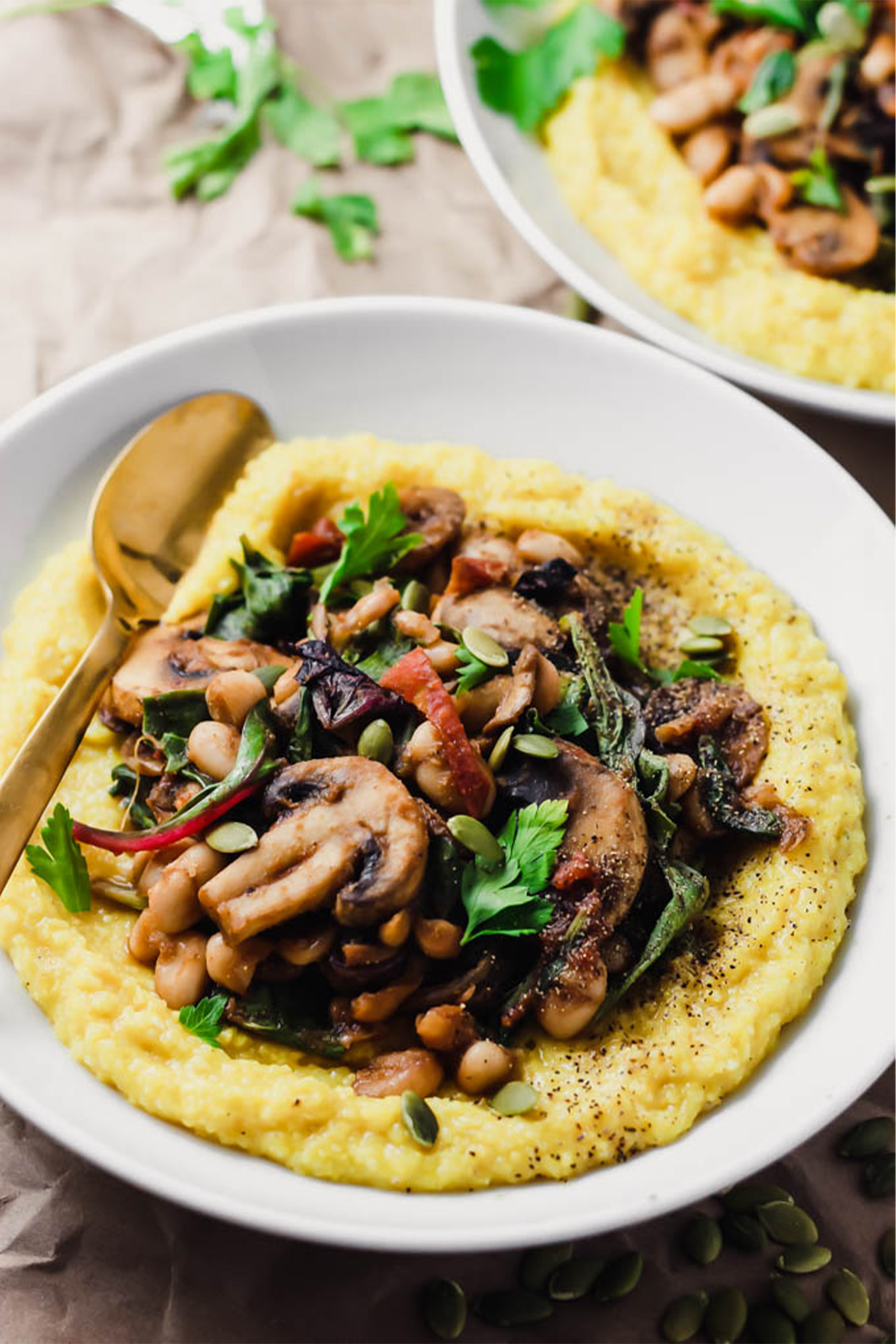 a plate of polenta topped with beans, mushrooms and spinach