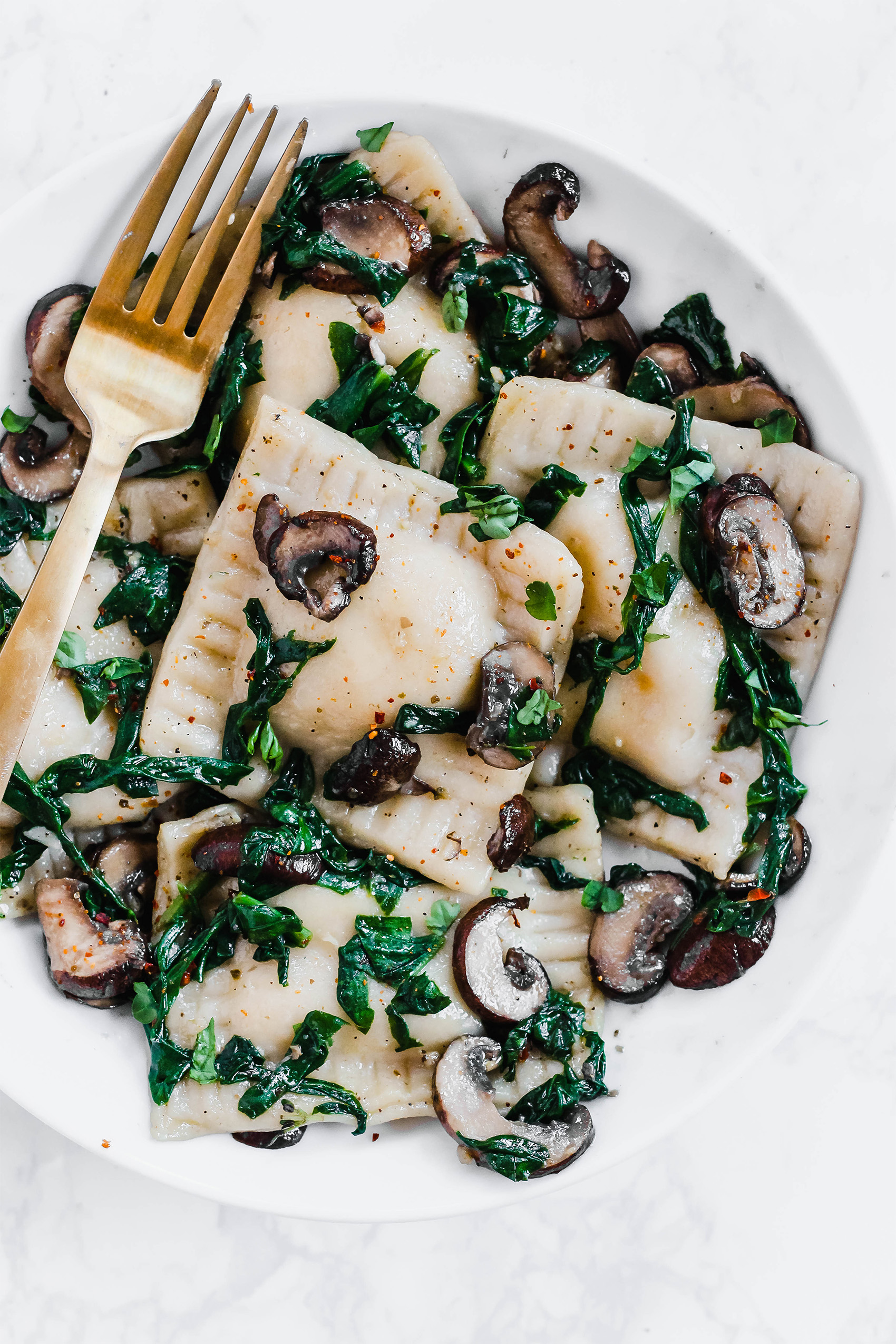 a plate of vegan ravioli served with sauteed mushrooms and spinach