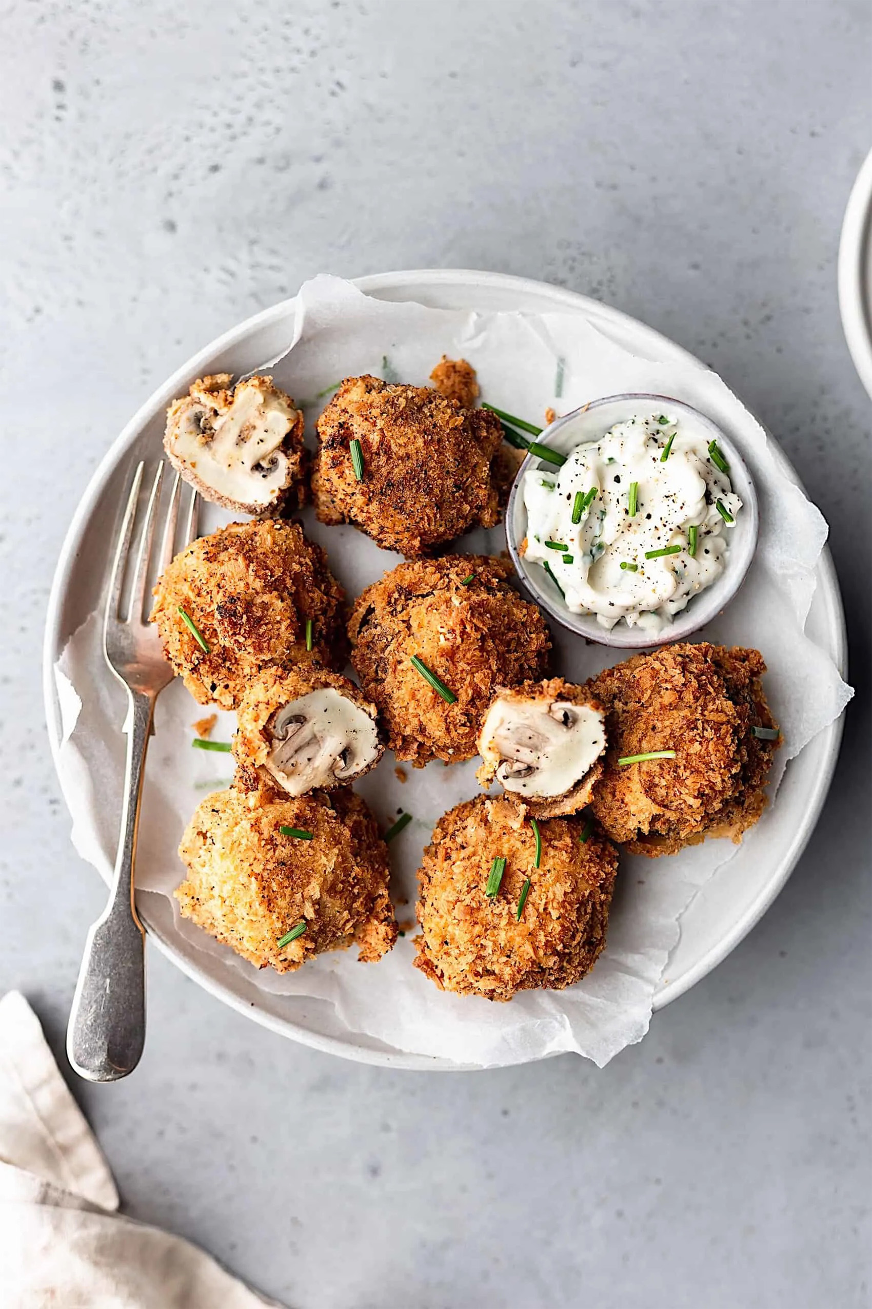 a plate of fried mushrooms served with a creamy dipping sauce