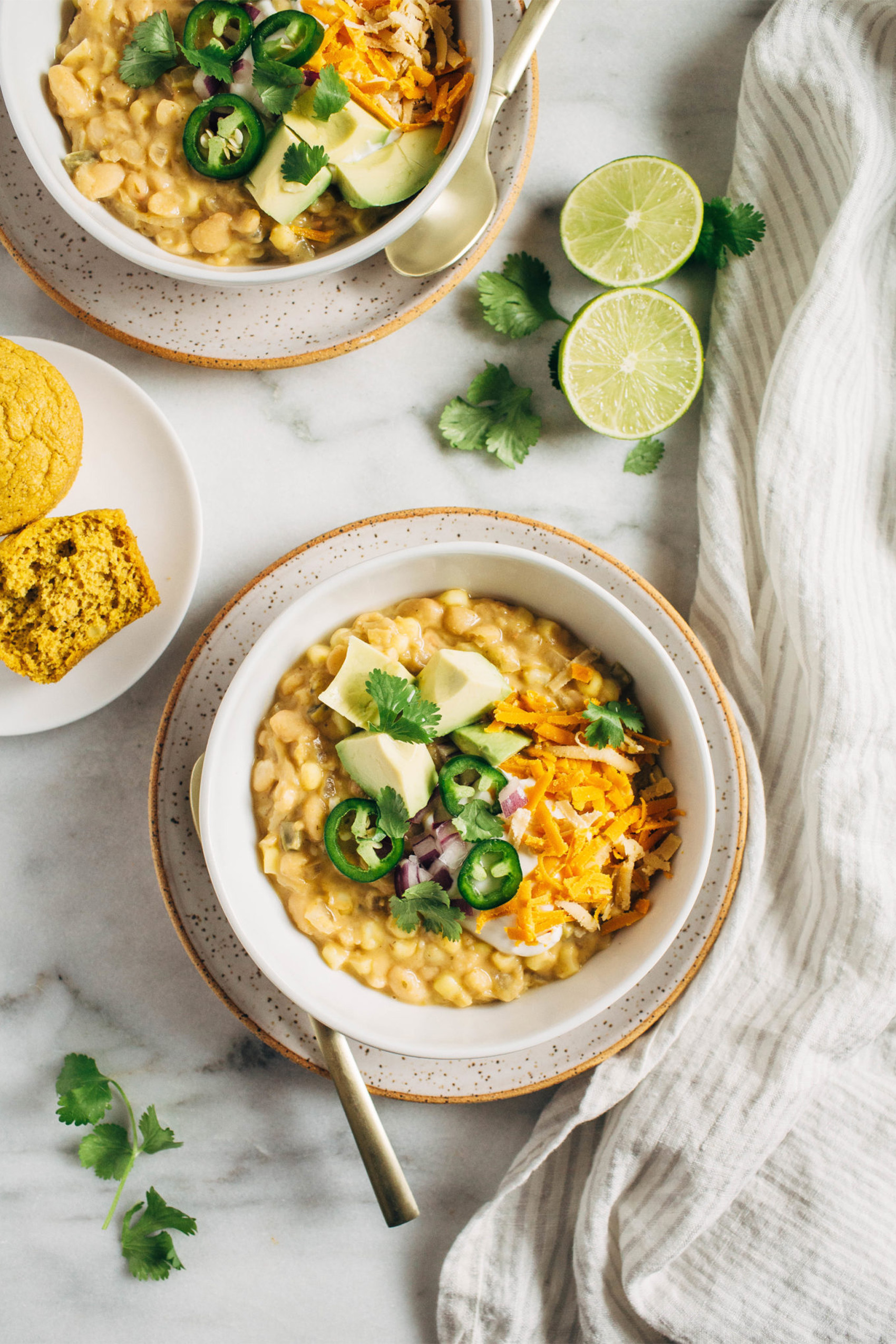 a bowl of white bean chili topped with avocado and sliced jalapenos