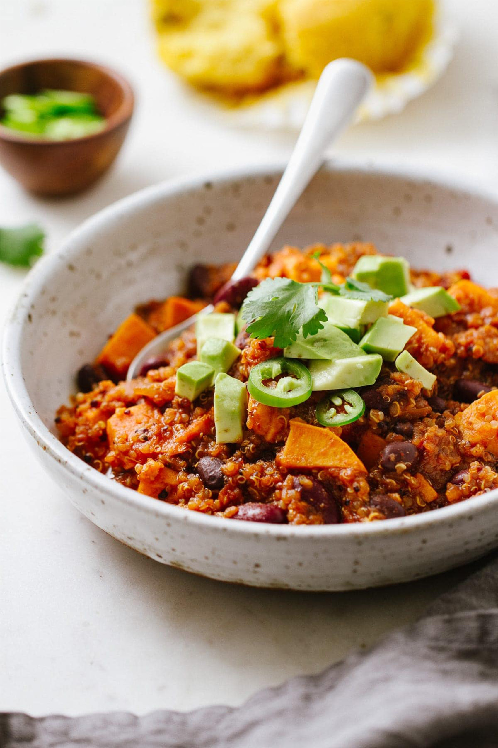 a close up of a bowl of sweet potato chili topped with diced avocado