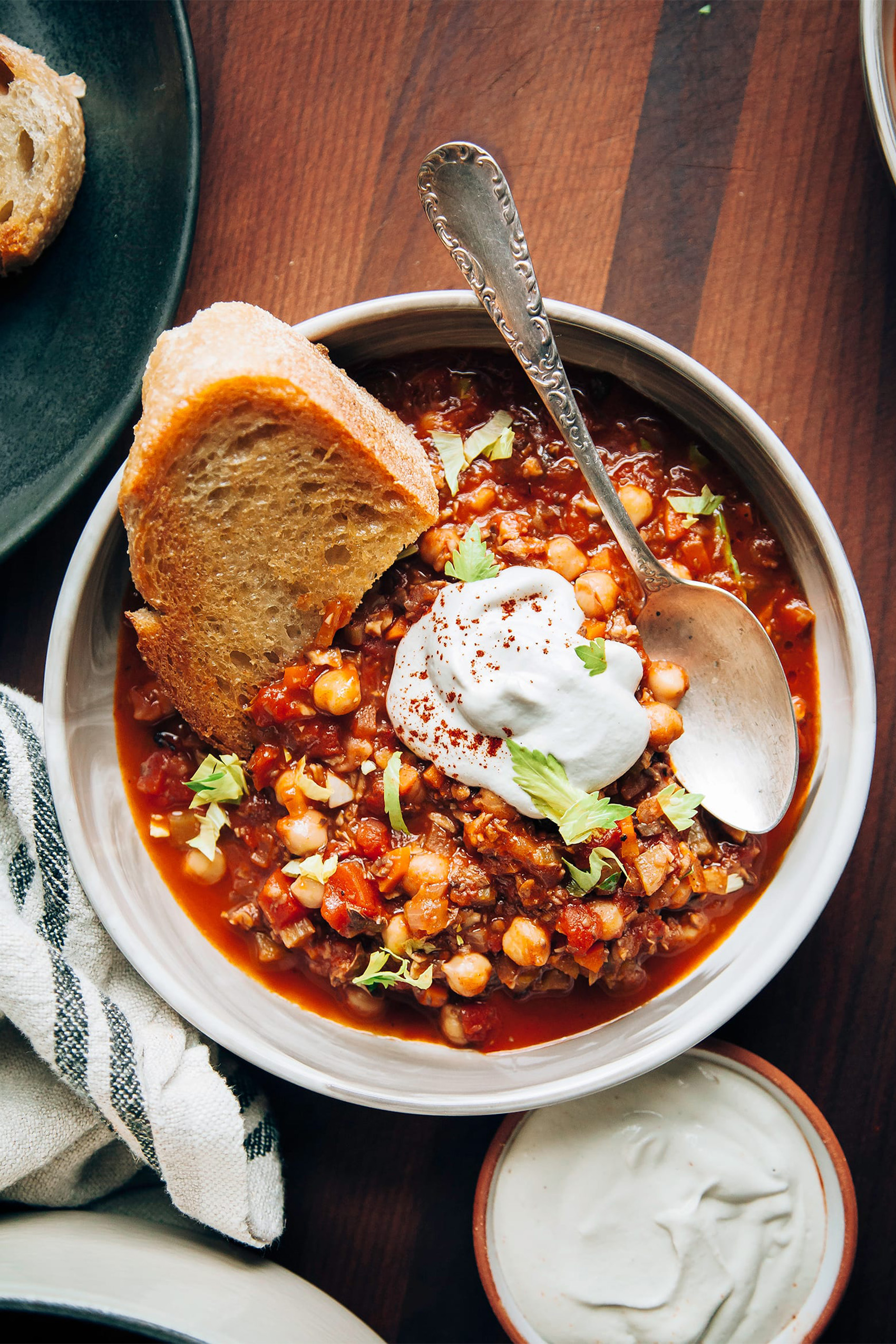 a bowl of vegetarian chili served with a slice of bread and a dollop of sour cream