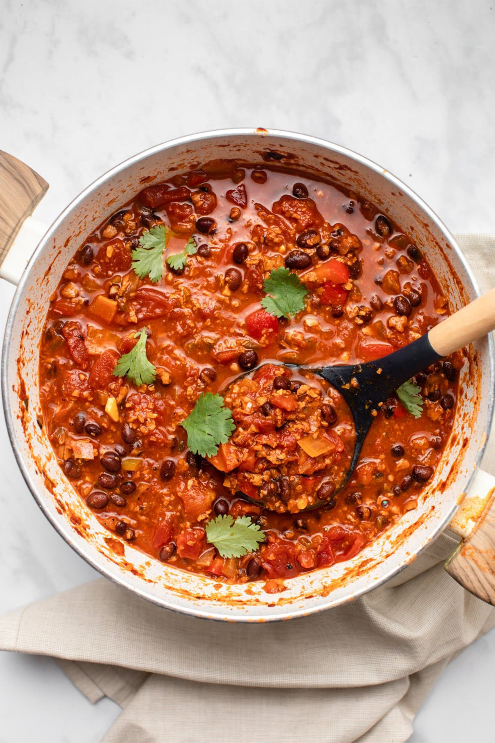 a bowl of vegan chili being served with a ladle