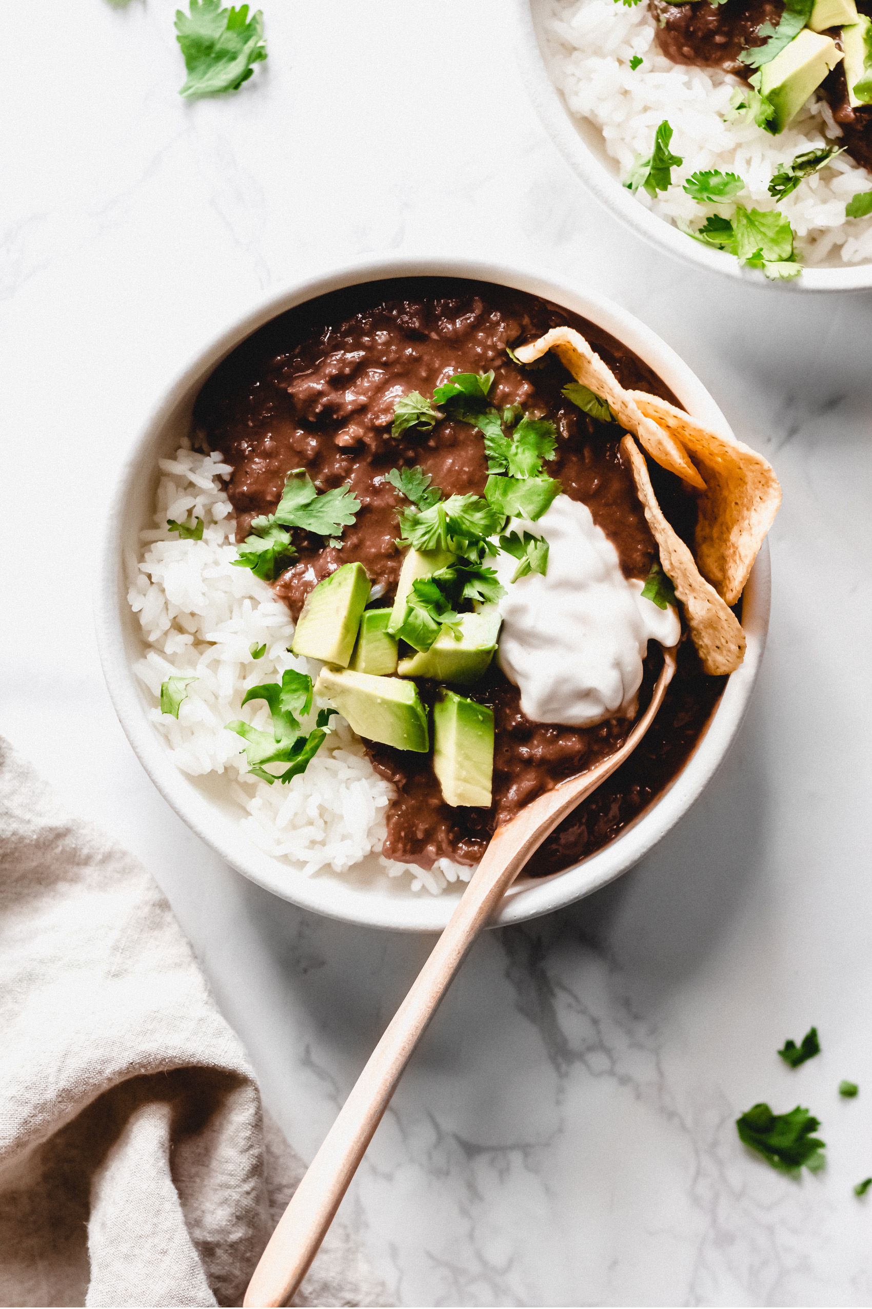 a bowl of black bean soup served with tortilla chips, avocado and cilantro