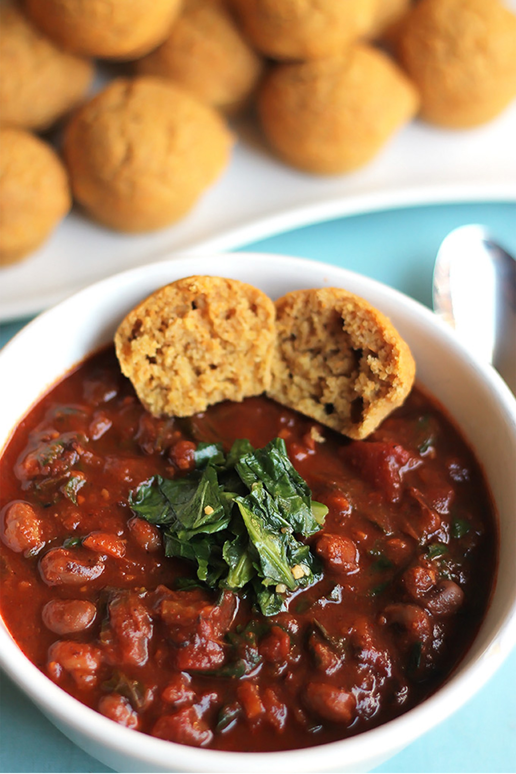 a bowl of red bean chili served with a mini cornbread muffin