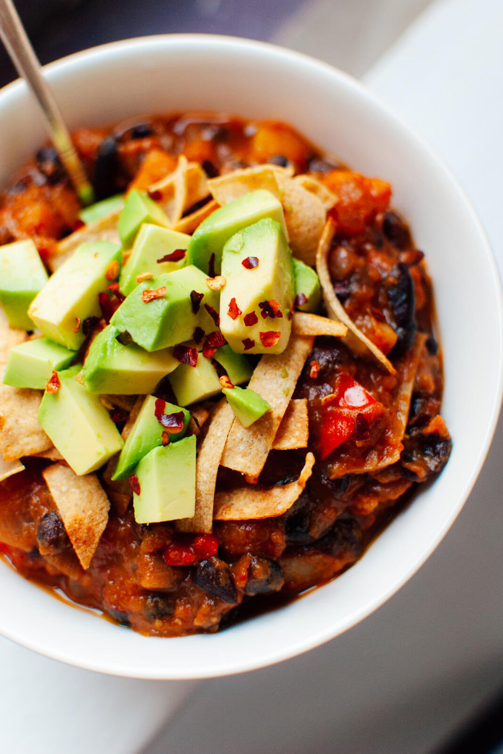 a bowl of vegan chili topped with avocado