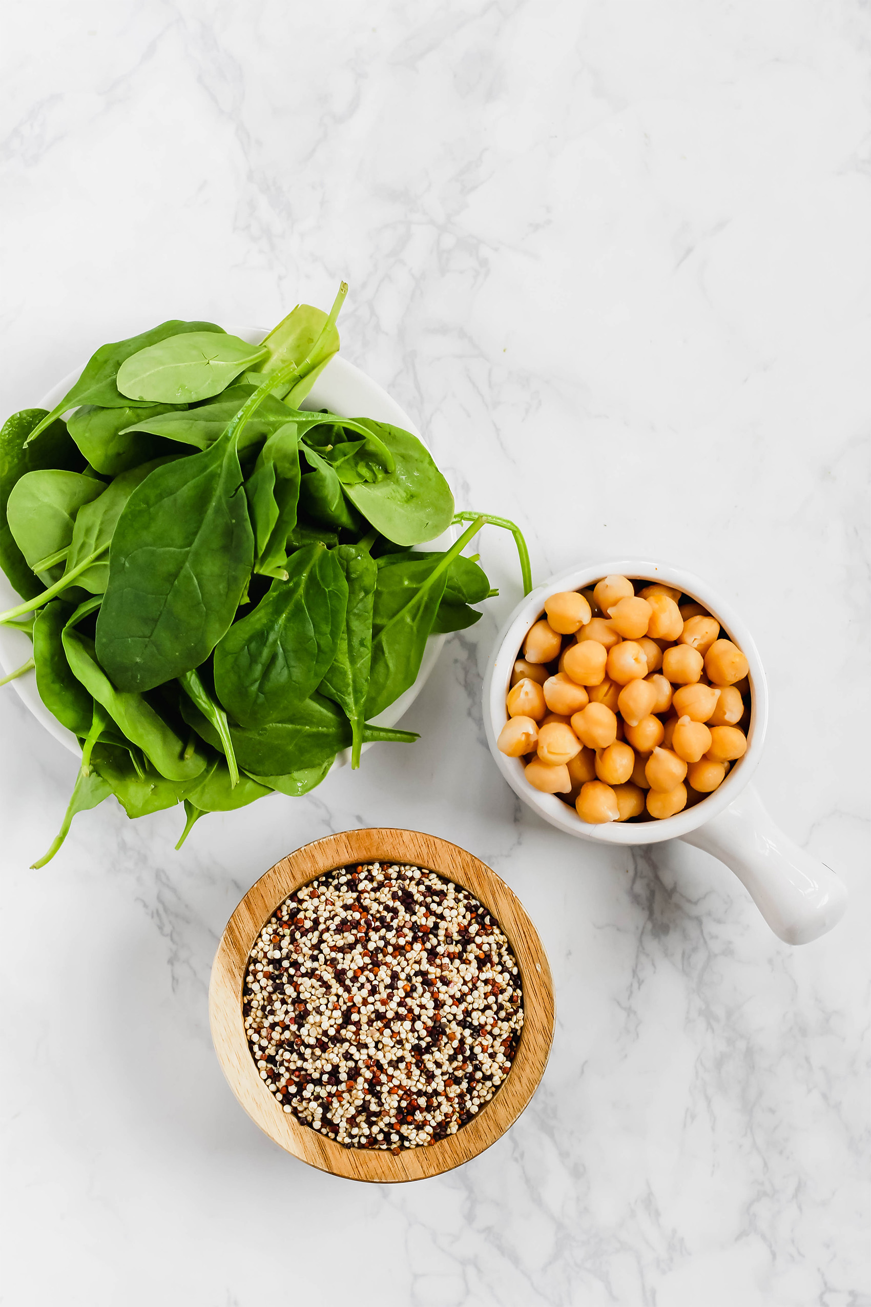 a cup of chickpeas, a bowl of dried quinoa and a bowl of baby spinach