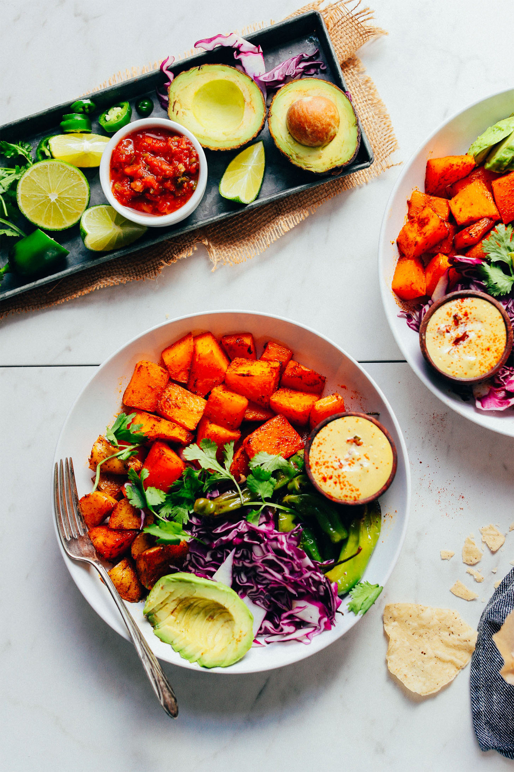 a bowl of cubed butternut squash, cabbage, avocado and herbs