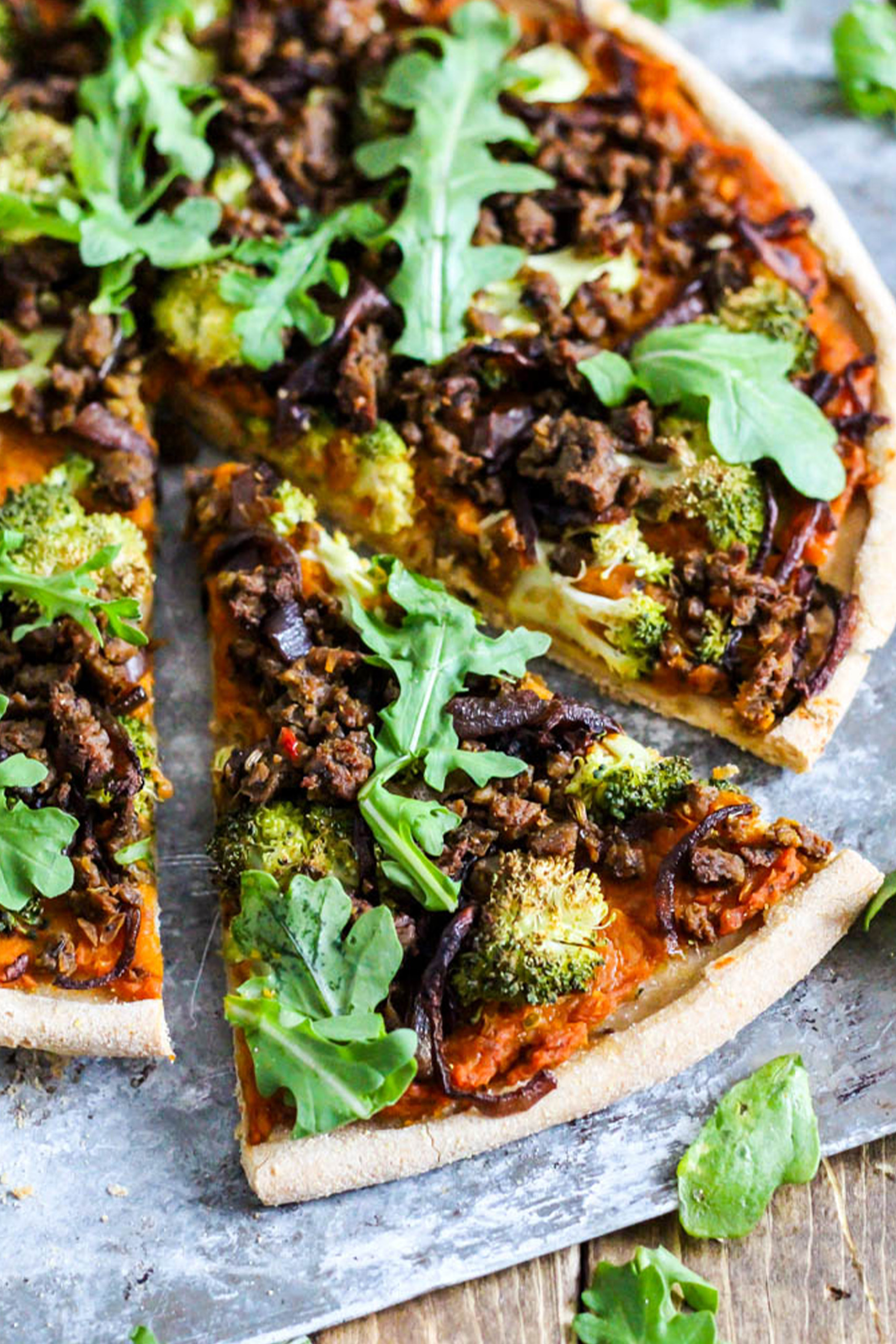 a vegan pizza with butternut squash, arugula and broccoli