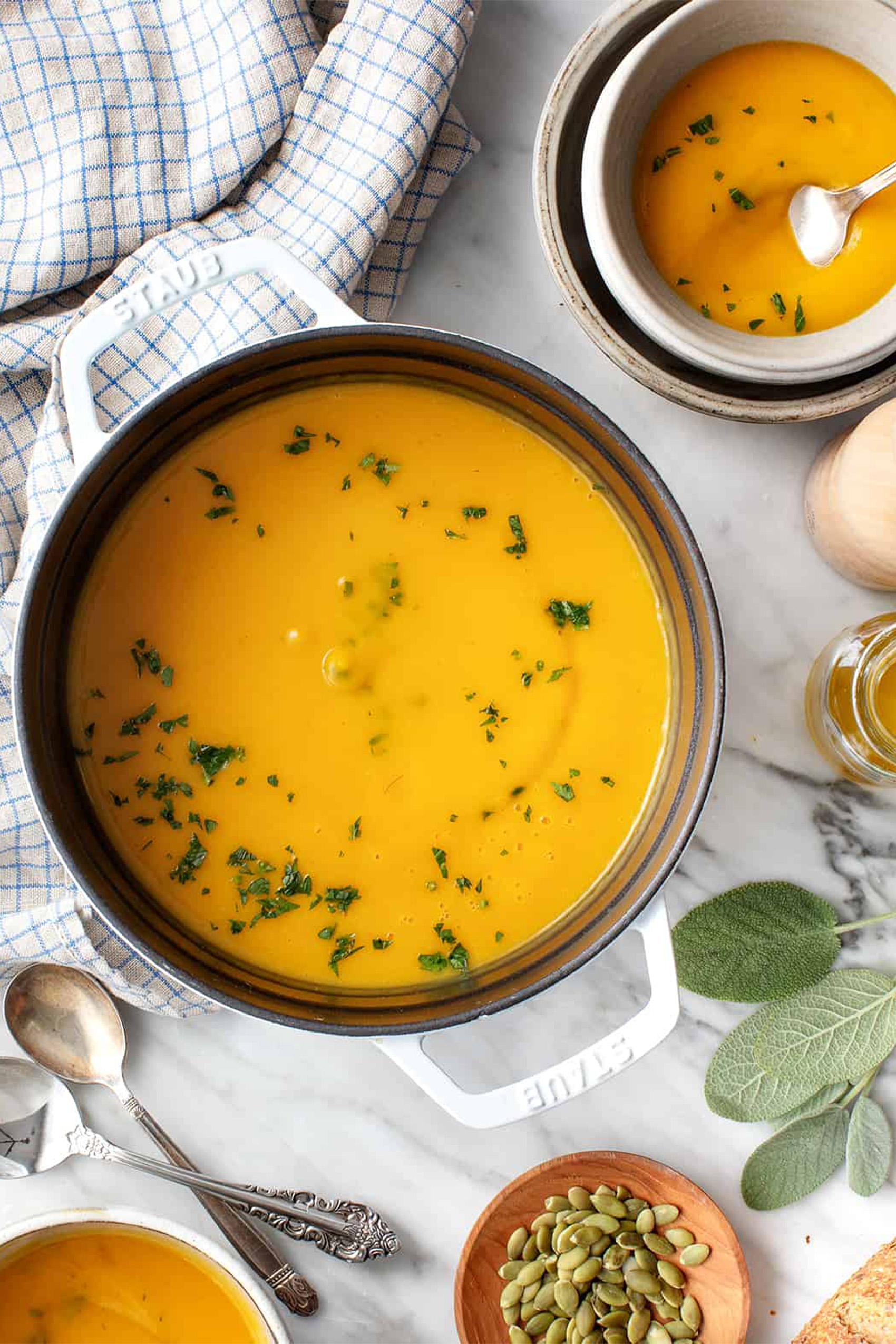 a pot of vegan butternut squash soup topped with fresh herbs