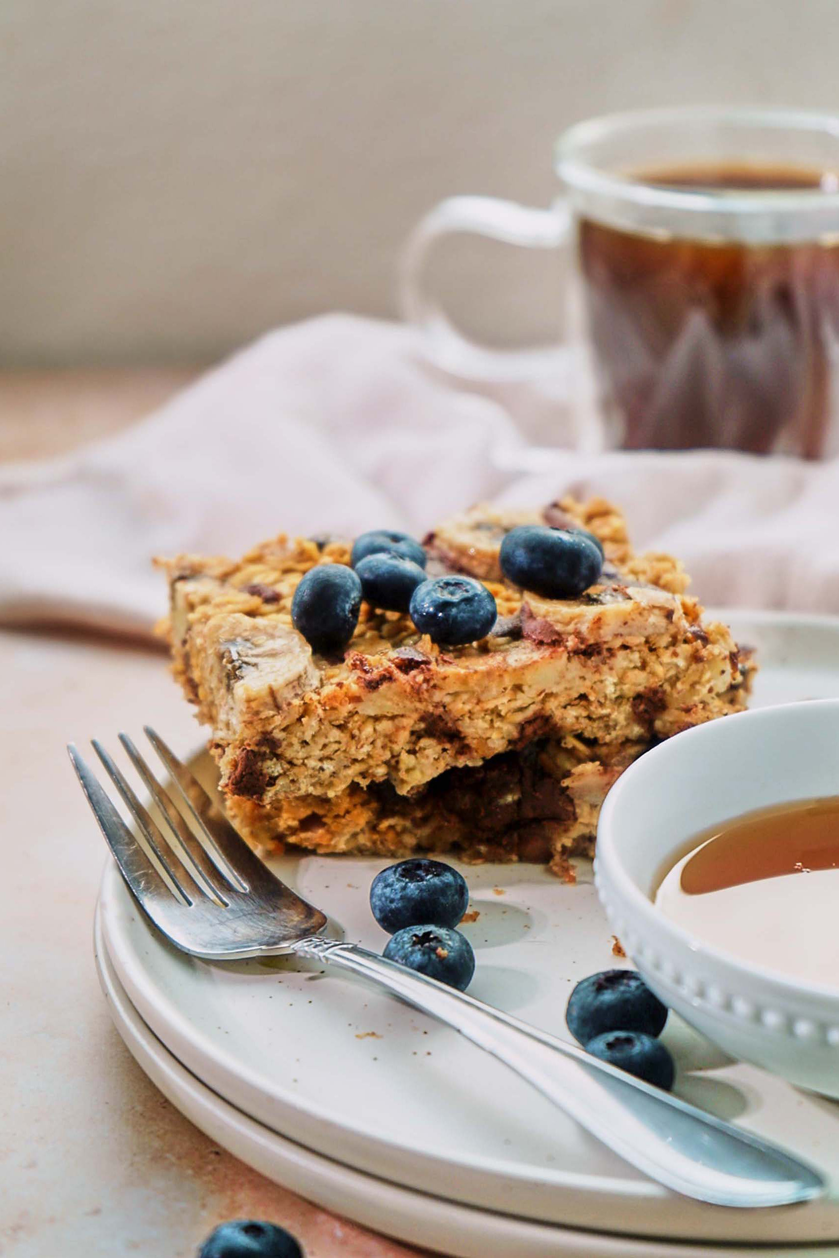 a slice of vegan chocolate chip banana baked oatmeal topped with fresh blueberries