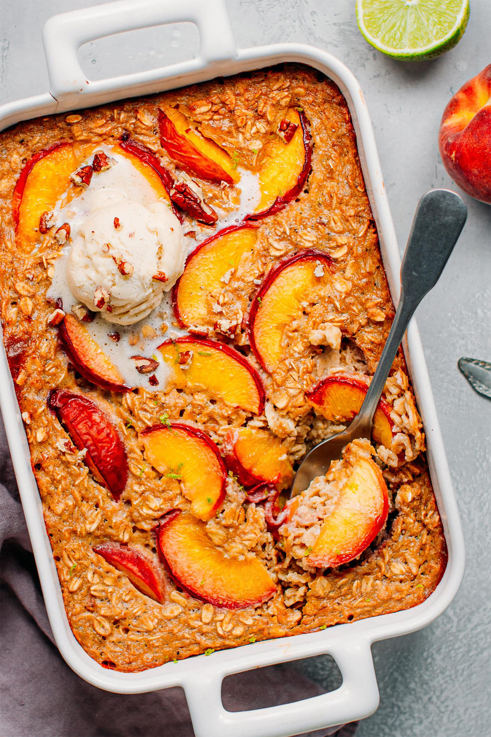 a spoon taking a scoop out of a dish of peach baked oats