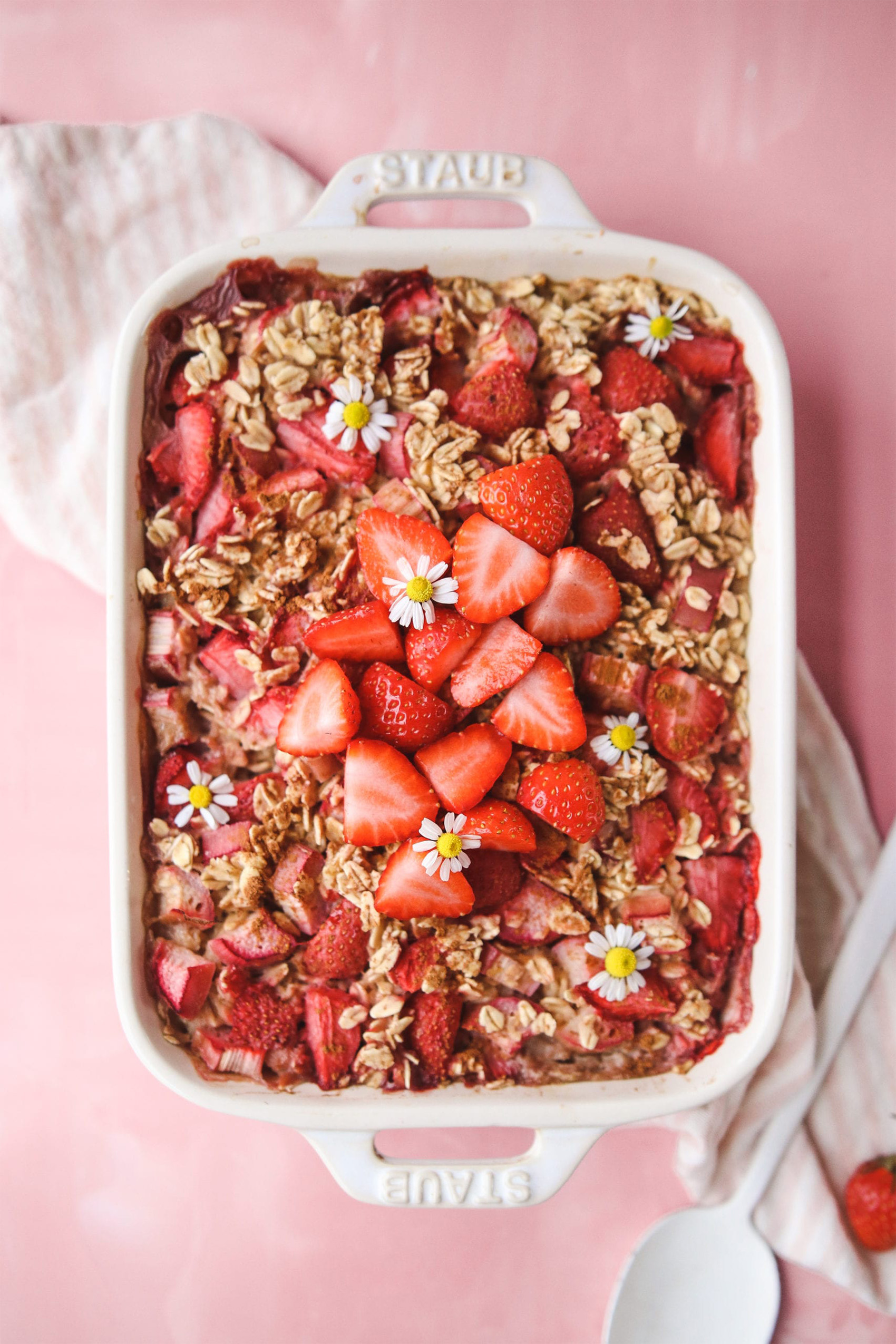 a baking dish filled with baked oatmeal topped with halved strawberries