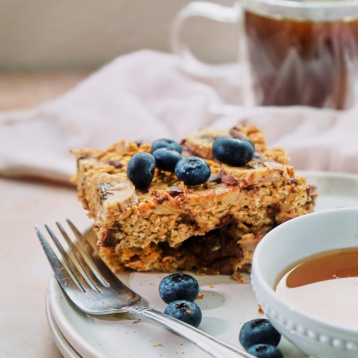 a plate with a serving of banana chocolate chip baked oatmeal topped with fresh blueberries